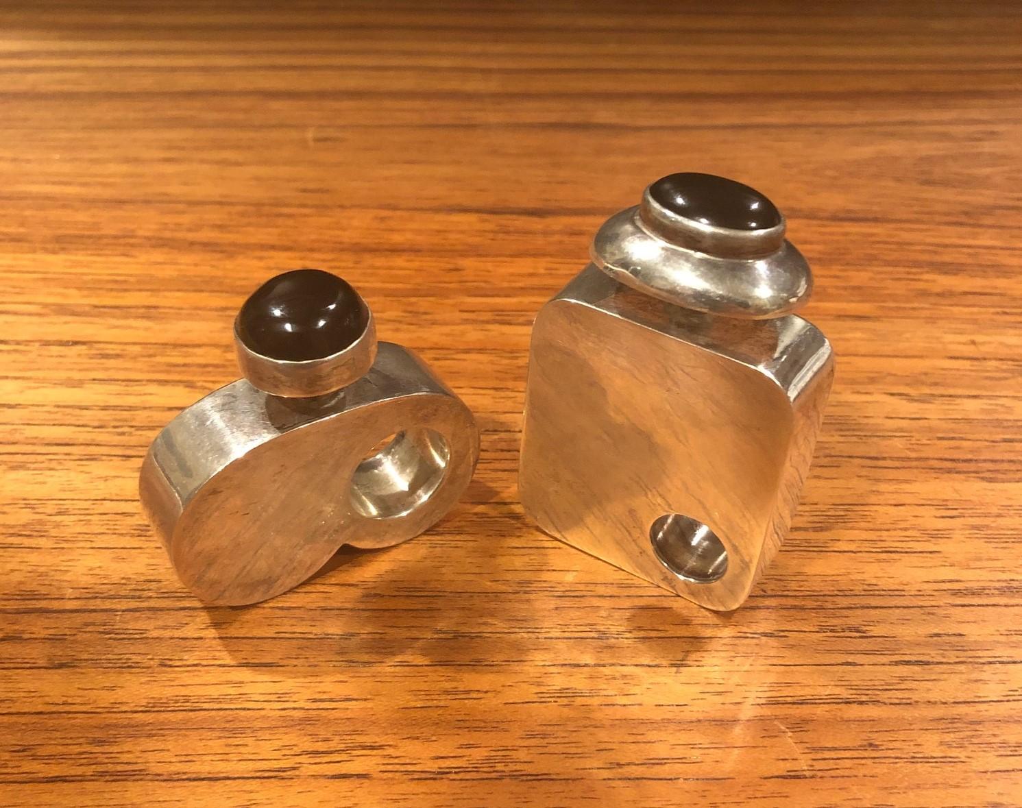 Pair of modernist sterling silver perfume bottles from Taxco, Mexico, circa 1980s.

The bottles have an elegant modernist design in a heavy gauge of sterling silver with faceted onyx top. The larger bottle is marked 