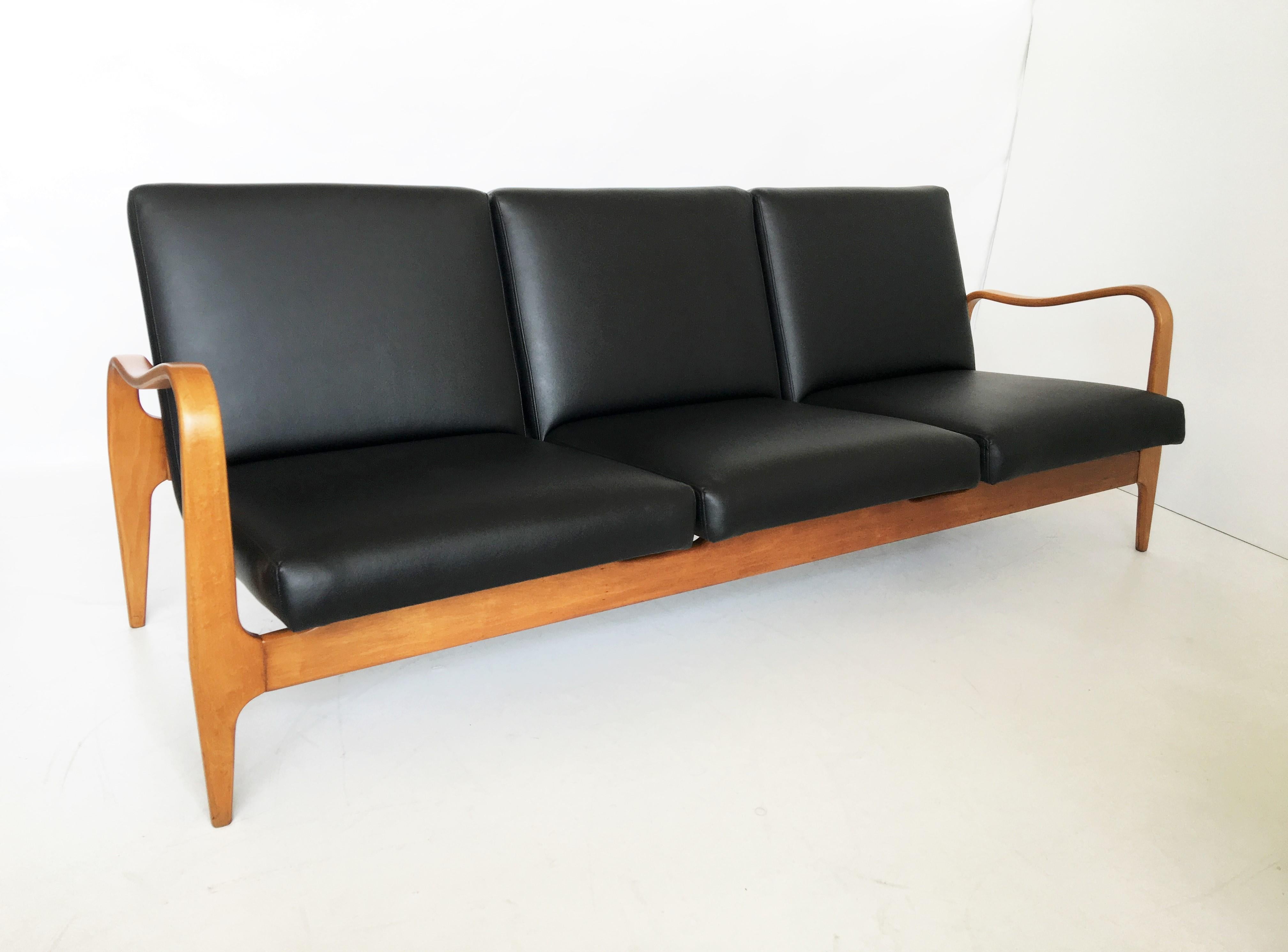 A great pair of vintage Thonet bentwood three-seat settee sofa couch. Features a super stylish organic curved line bentwood arm frame, brass accent details, and upholstered in black.