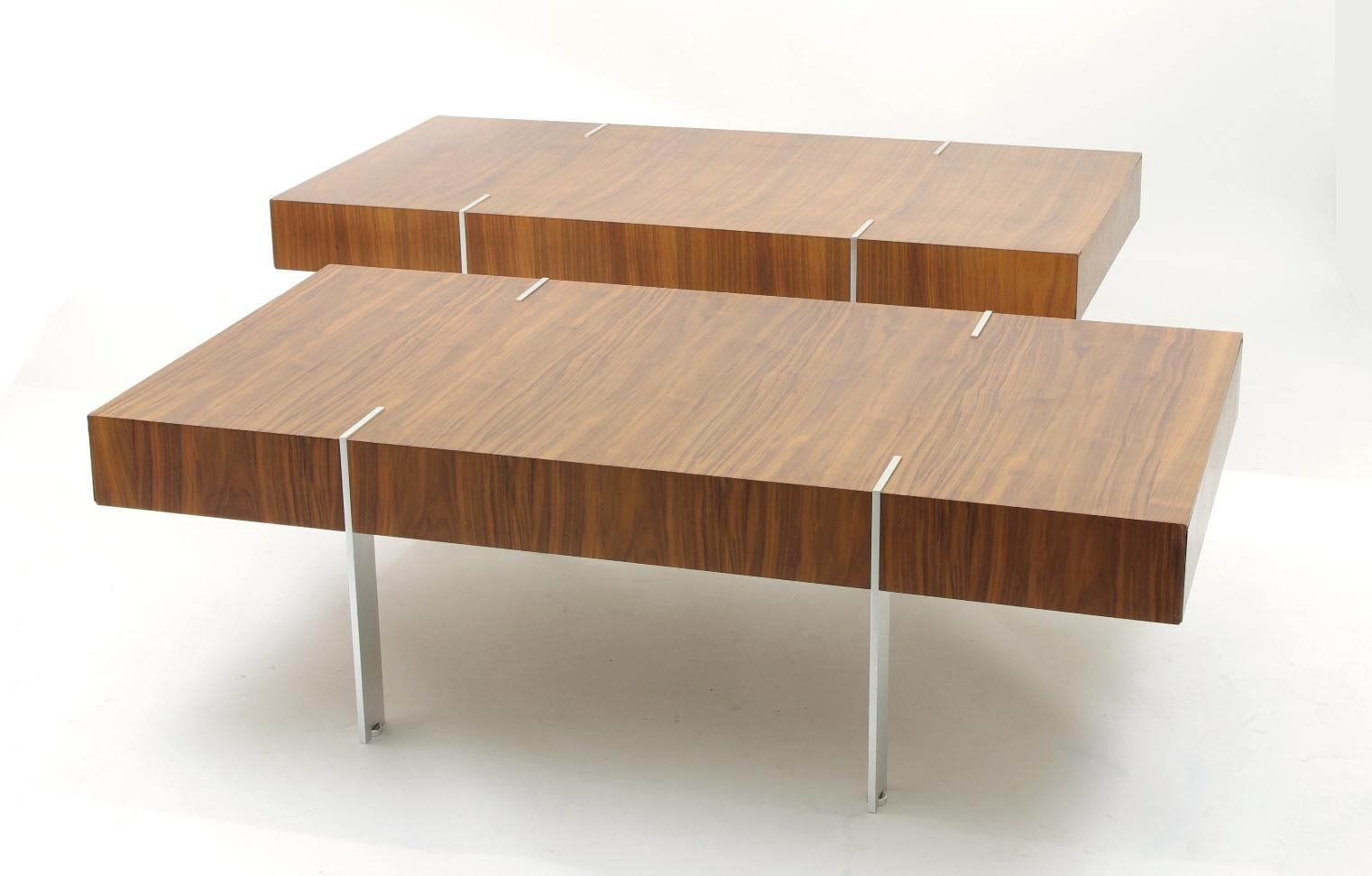 Pair of modernist walnut coffee tables, each with bookmatched veneer; the ends with concealed drawers; the plated legs with adjustable disc feet.