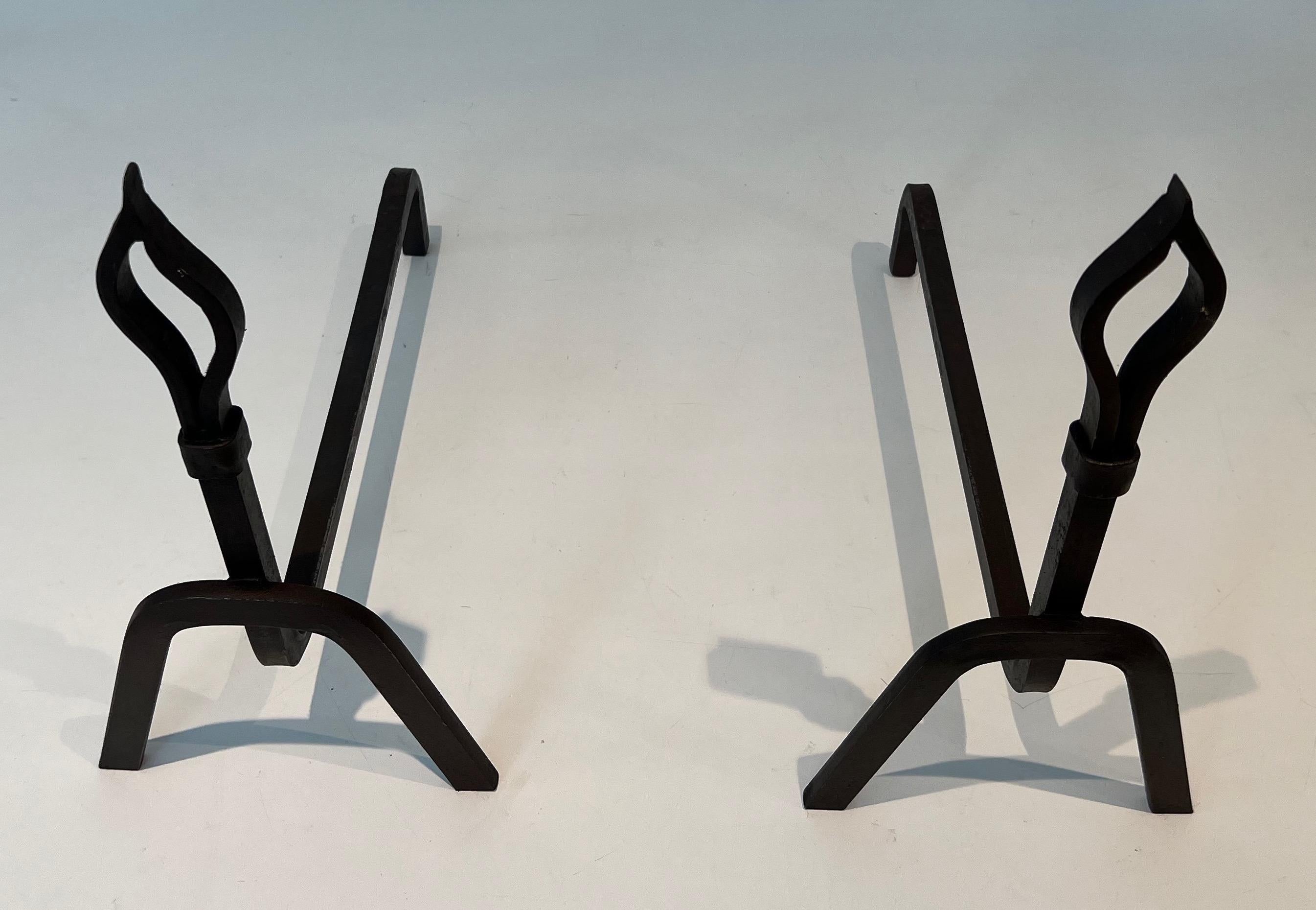 This very nice and unusual pair of modernist andirons is made of wrought iron. This is a nice work with design flames on top. this is a French work. Circa 1950