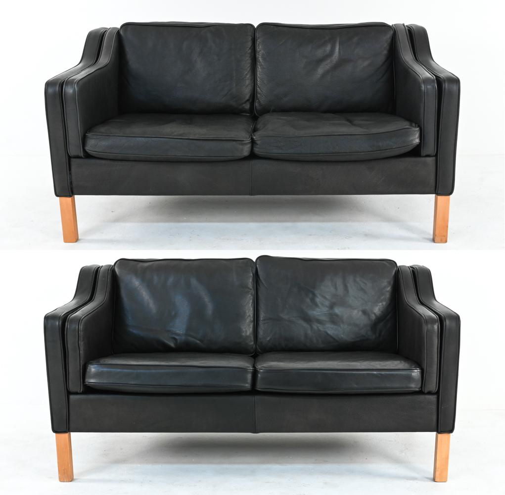 An attractive pair of Danish modern two-seater loveseats in black pebbled leather, by Mogens Hansen. Produced after Borge Mogensen's iconic design, these sofas feature gently sloping sides with austere, refined silhouettes. On sturdy blonde