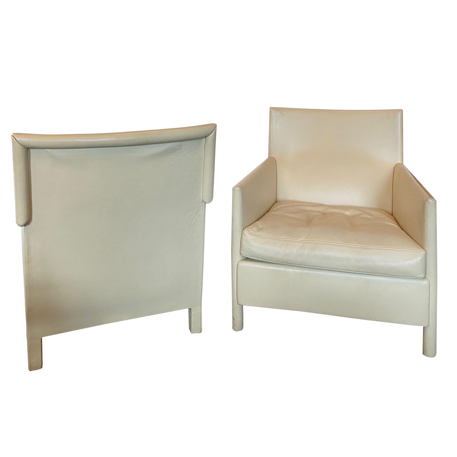 Pair of exceptionally comfortable lounge chairs in leather that is cream, ivory or light khaki in color.  Lovely shape with moderate proportions and leather wrapped legs.  Loose seat cushion is down-filled and sits within a slender angular frame