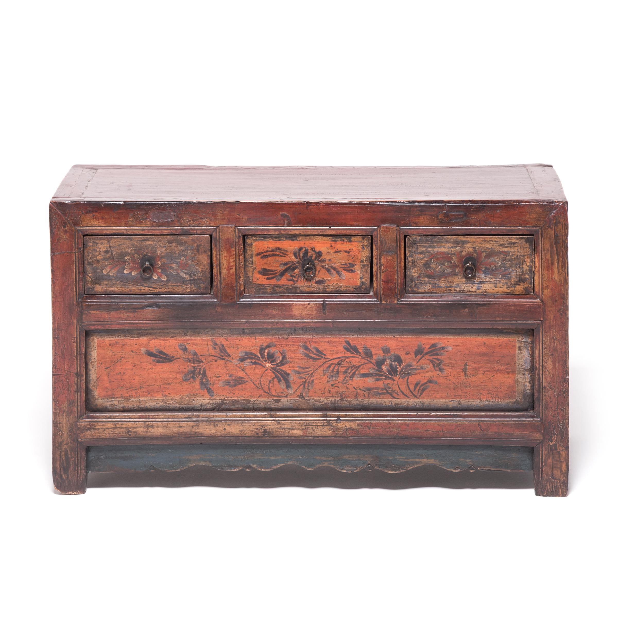 This pair of Provincial 19th century low chests from Mongolia were crafted of pine and cloaked in layer upon layer of rich red lacquer. The drawers were then hand-painted with graceful flowers and trailing vines, accented by simple brass hardware.