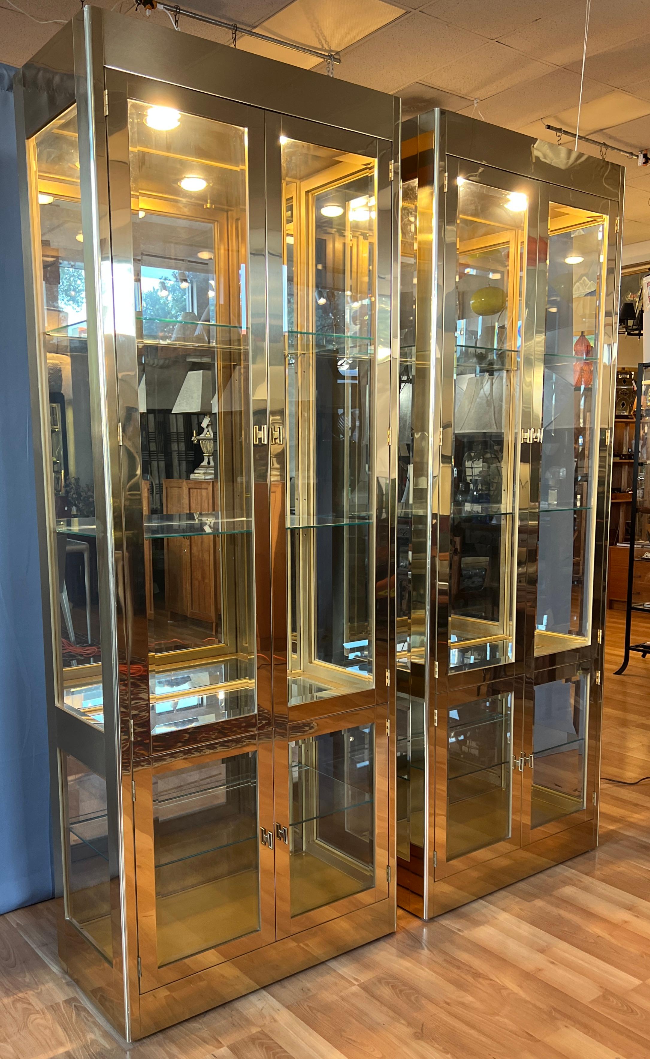 Offered here are a pair of stunning and monumental 1970s Brass vitrines, by Mastercraft.

Two lacquered Brass vitrines, with two cabinets in each unit, both with a glass shelf in-between so the two spot lights with dimmers can shine through to the