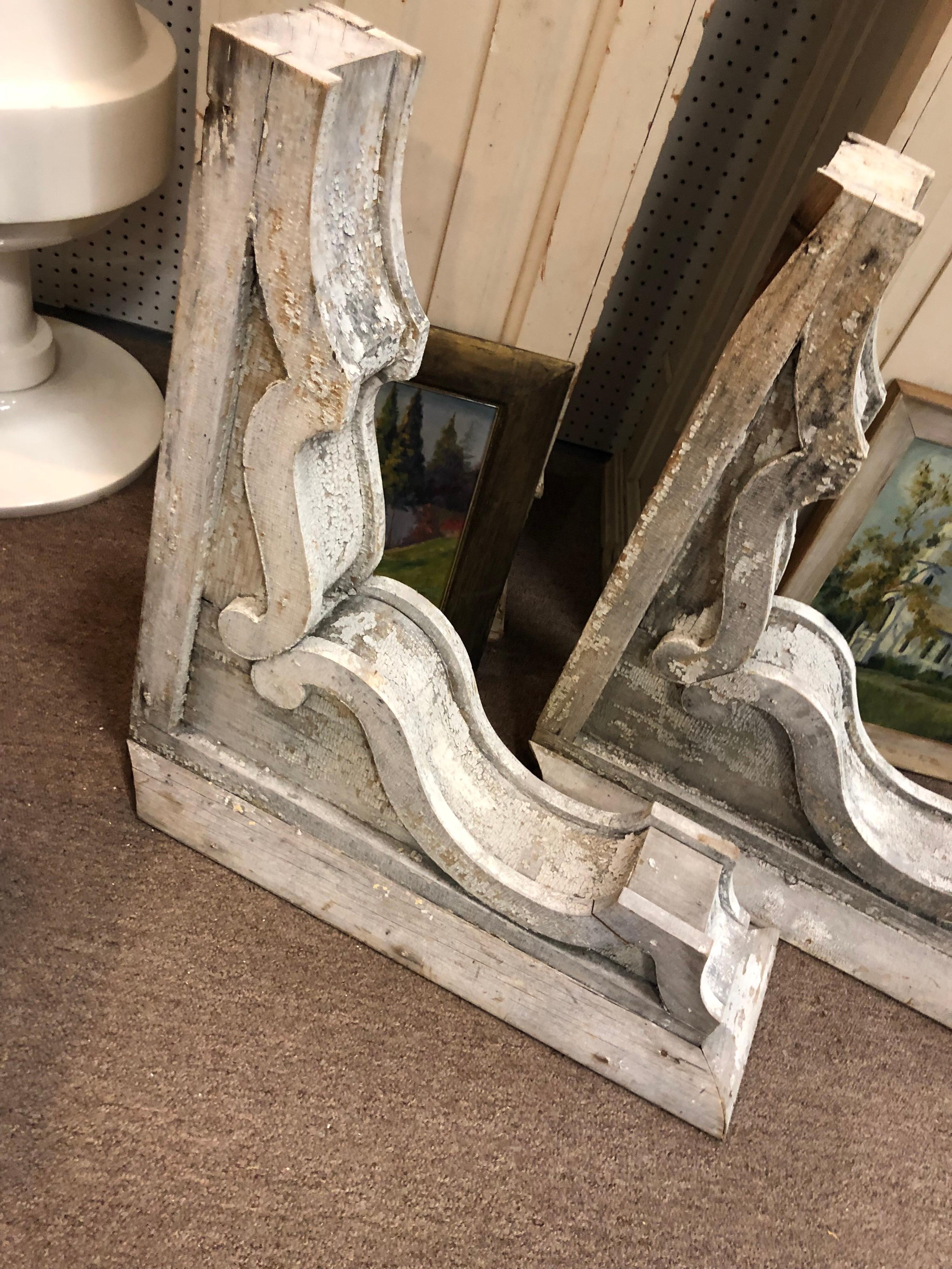 Pair of monumental antique farmhouse corbels. Chippy paint and faded whitewash color. Some seams are loose but can be reinforced. Use as ends to create a shelf or just mount as an architectural piece in your home. They came out of the Historic