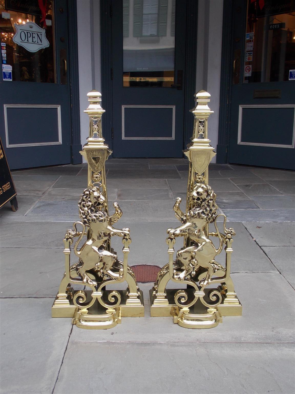 Pair of Monumental English brass molded edge two tiered floral medallion andirons with perched flanking lions, scrolled decorative adjacent beaded legs, and resting on step back rectangular plinths with rear supports, Early 19th century.