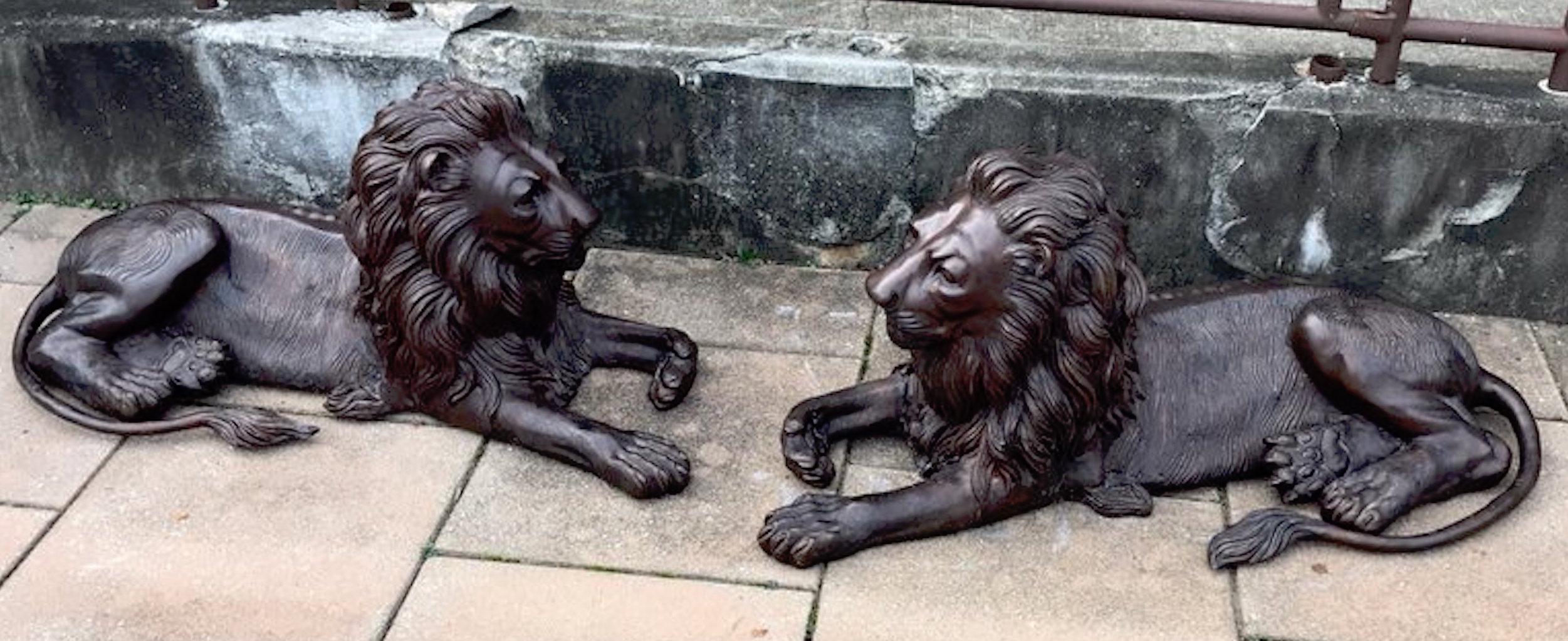 Pair of monumental bronze recumbent lions, each one finely detailed in resting pose.