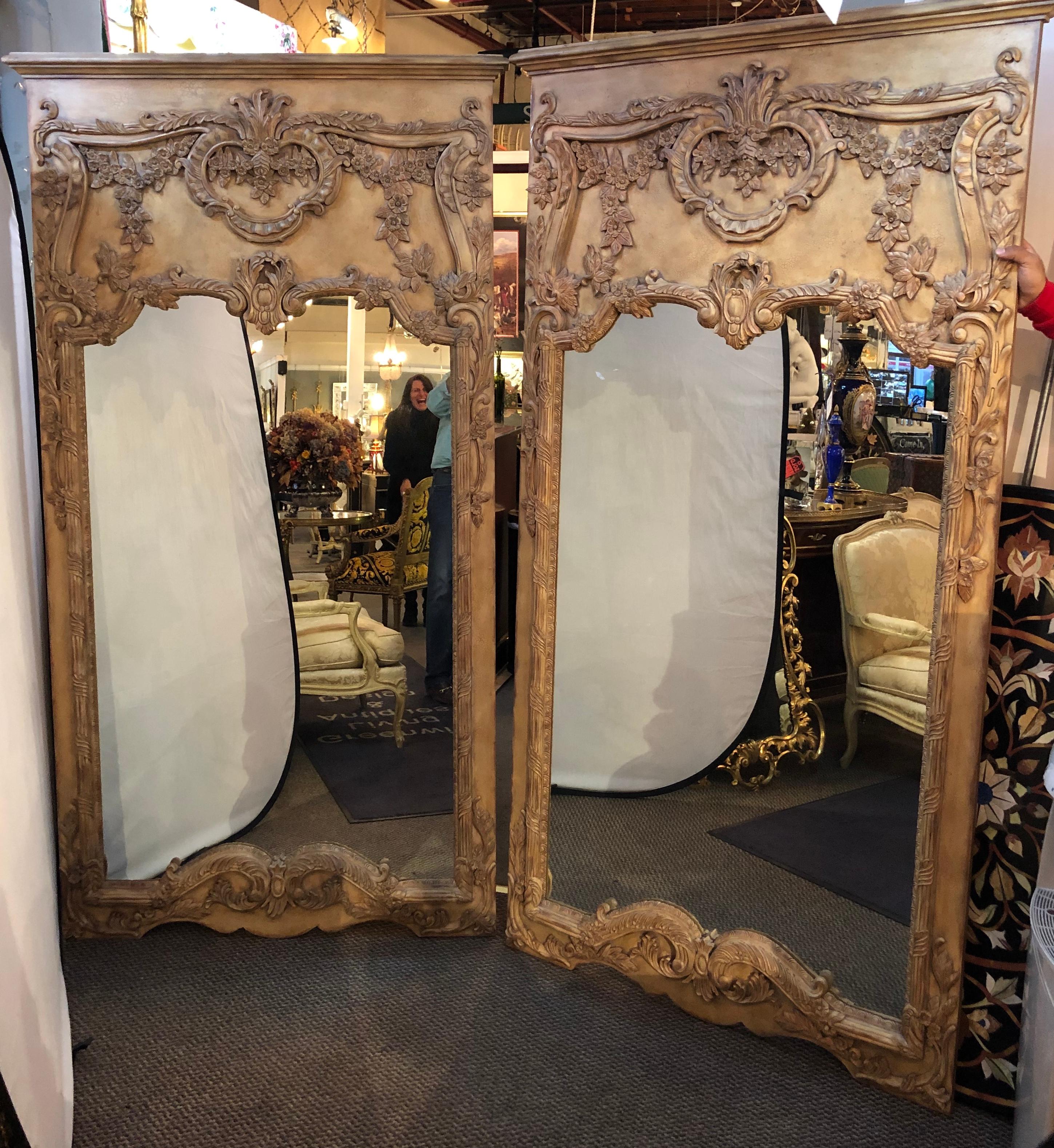 Pair of monumental finely carved custom mirrors depicting roses, leaf and floral design. Each of this fine carved mirrors have a clear centre panel on a long rectangular frame.