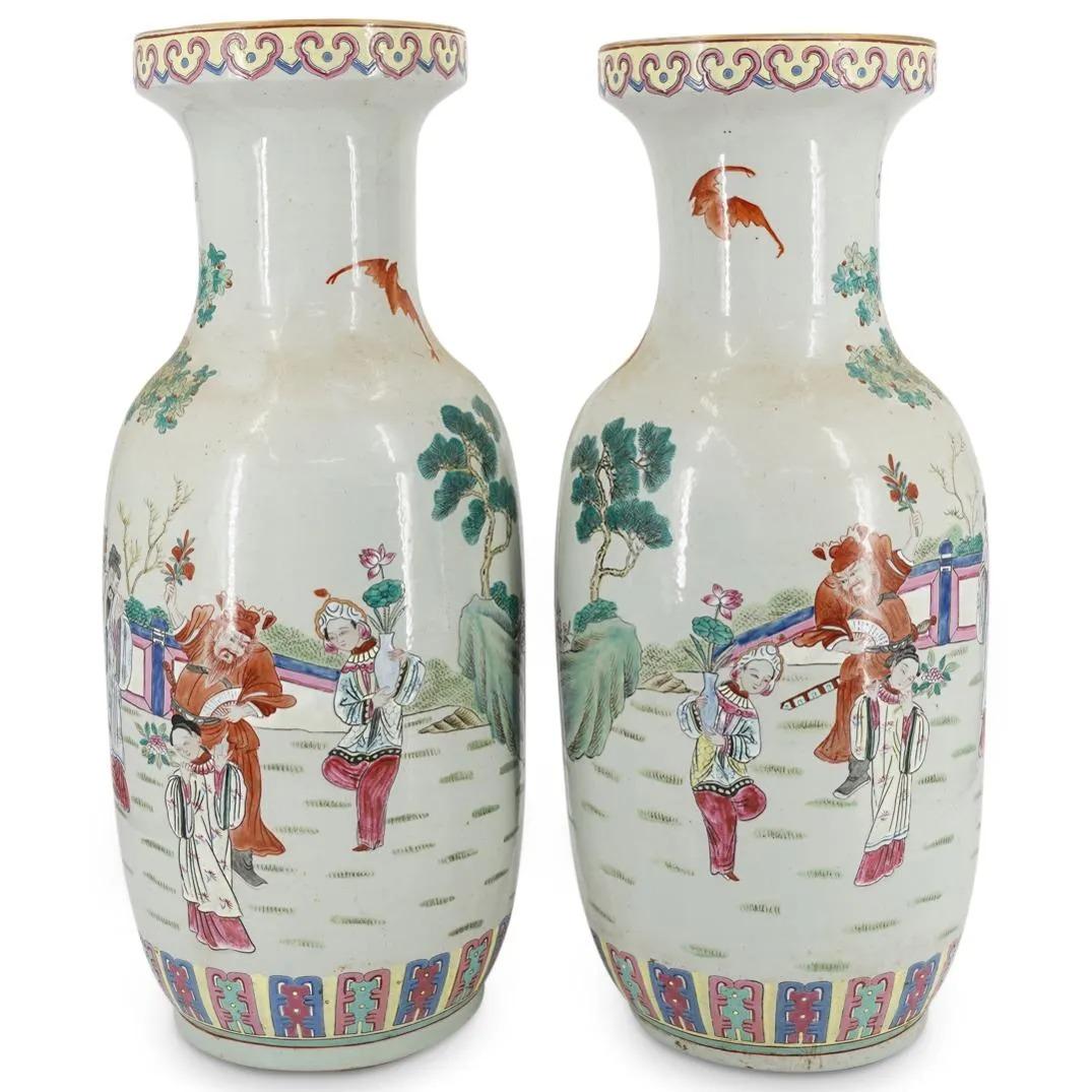 A pair of Chinese Famille Rose porcelain vases with an outdoor figural scene under flowering branches. Top of each vase is bordered with a curved geometric pattern and the base is bordered with a rectangular geometric pattern. Beautiful shades of