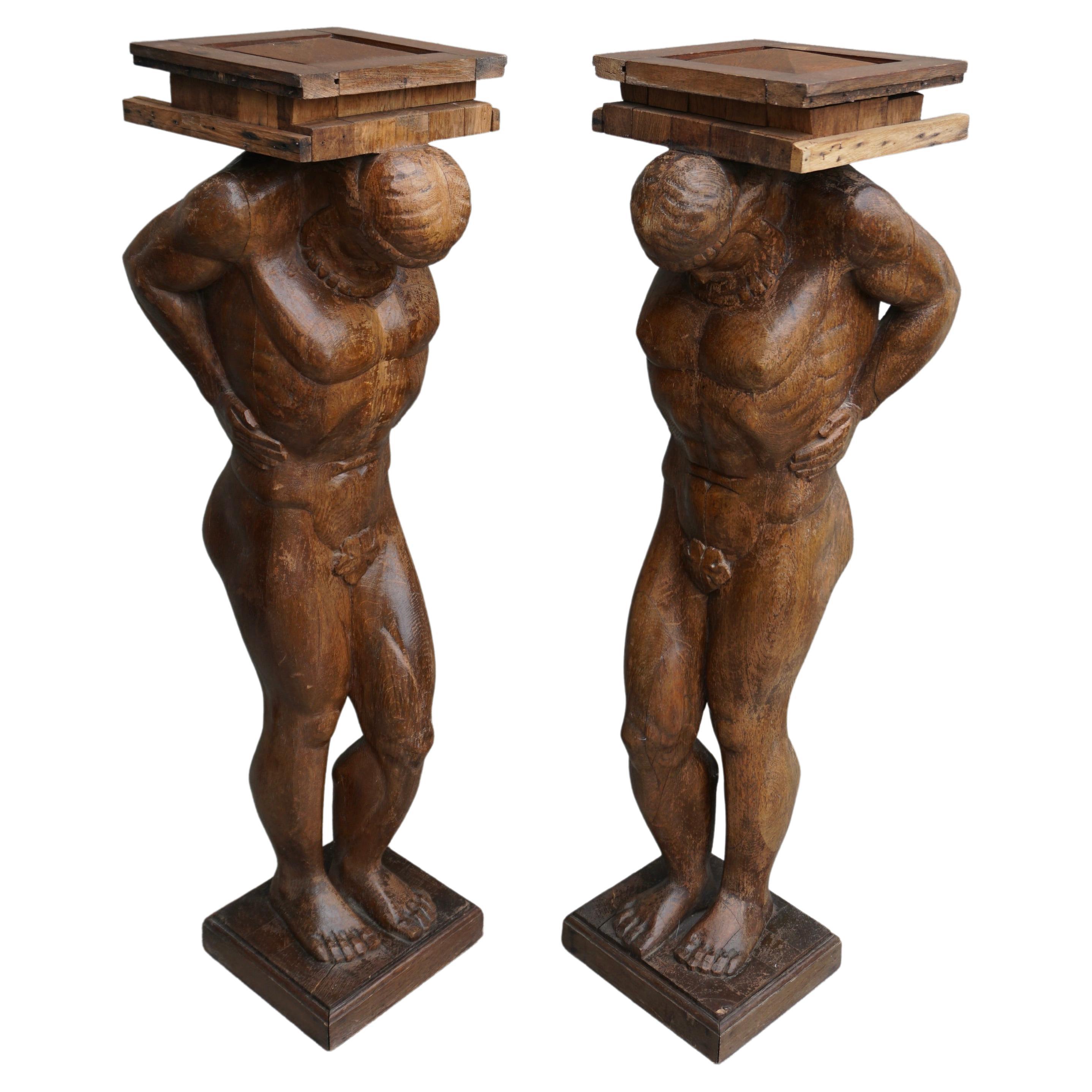 Two carved of oak columns or pedestals, each of a muscular male figure, representing Atlas or Hercules, the head inclined forward and supporting as well with the shoulders a square platform.

These stunning and beautifully crafted wooden sculptures