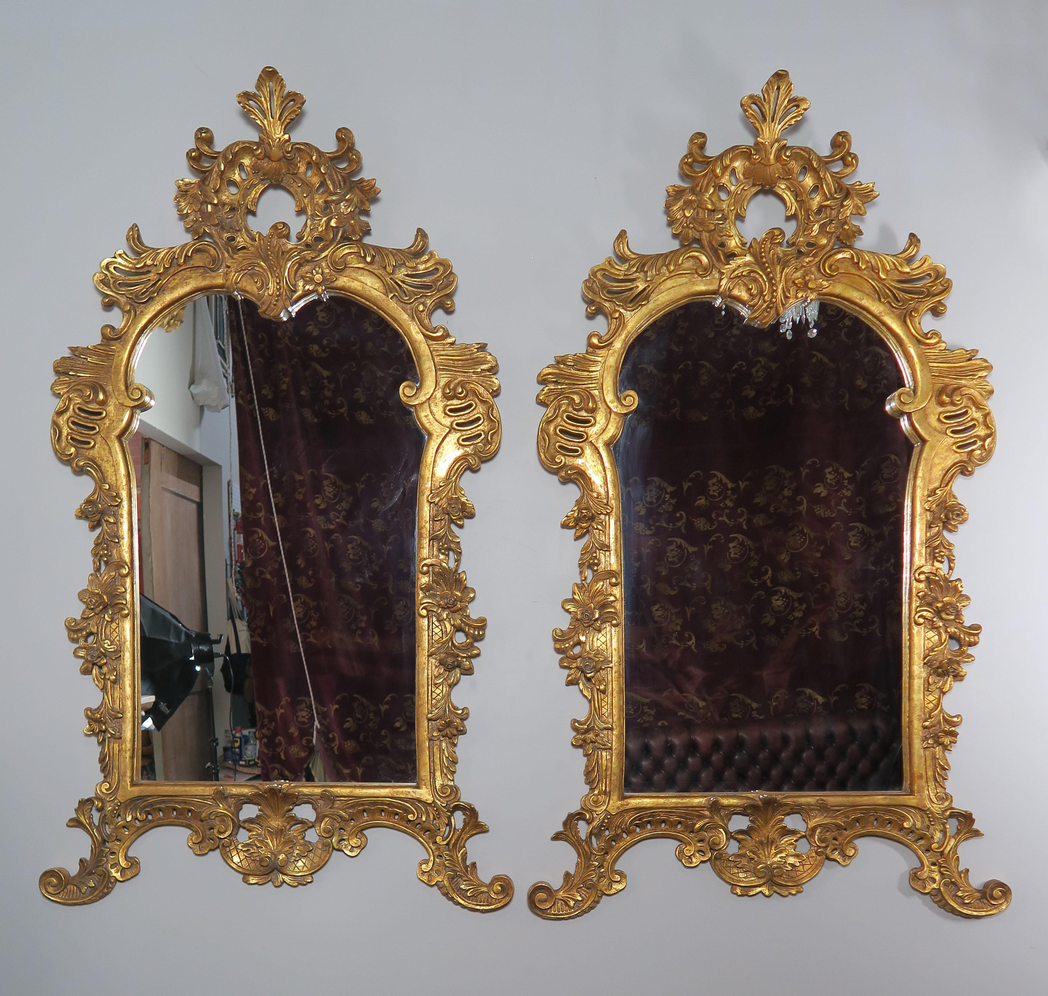 Pair of Monumental French Louis XV style giltwood mirrors intricately carved with acanthus leaves, scrolls and shells throughout. 22-karat gold leaf finish.