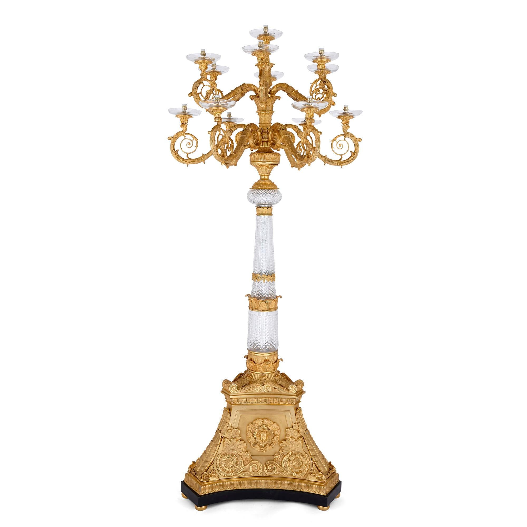 Pair of monumental gilt bronze and glass floor standing candelabra

Crafted in the neoclassical style, this pair of floor-standing candelabra are supported by three-sided plinth-form ormolu bases, which narrow towards the tops. The bases sit on