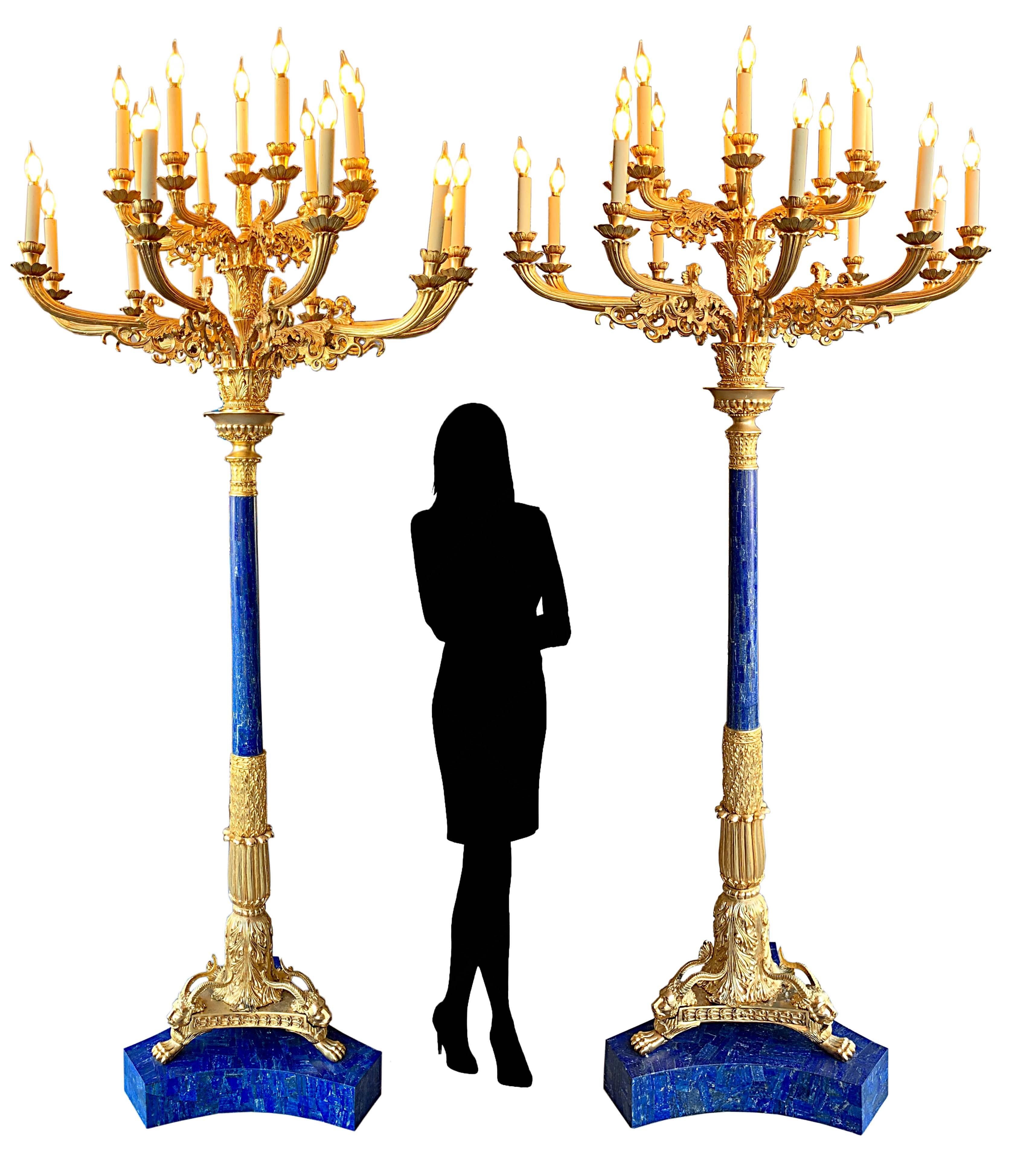 Une grande paire de lampes torchères à 19 lumières montées en bronze doré et en lapis-lazuli. Chacune d'entre elles est ornée de deux niveaux de branches en volutes et repose sur une base triangulaire, les supports se terminant par des pieds