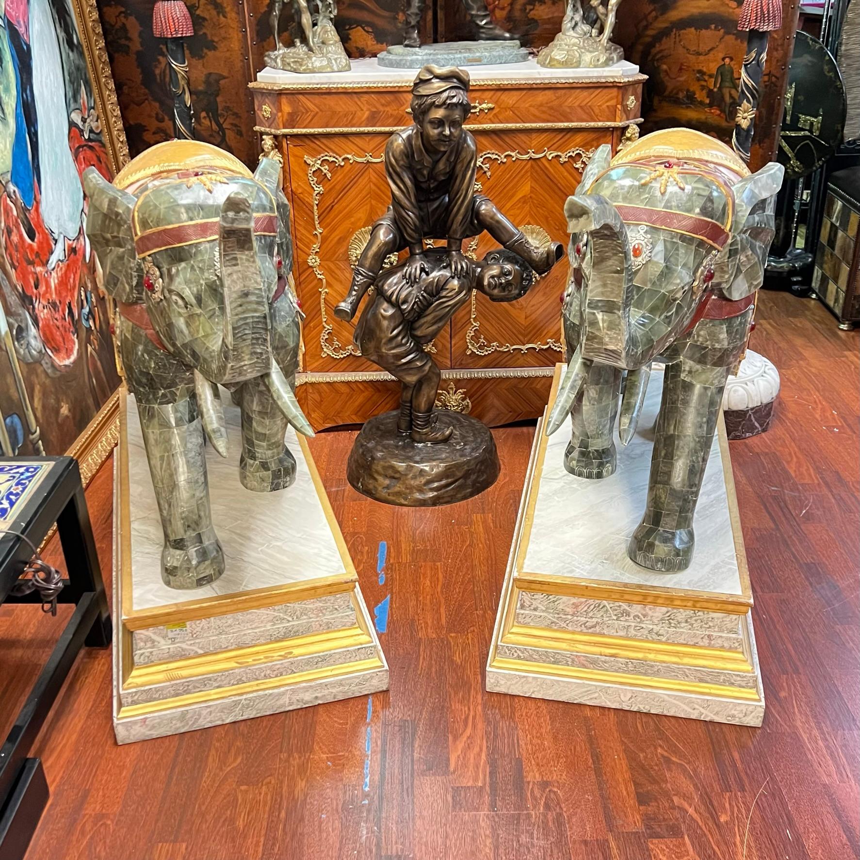 Pair of very large carved wooden elephants on stands, each 41 inches tall, clad with hardstone tiles and jewels and mounted on rectangular shaped bases with faux marble painted finish.  Apparently unsigned.