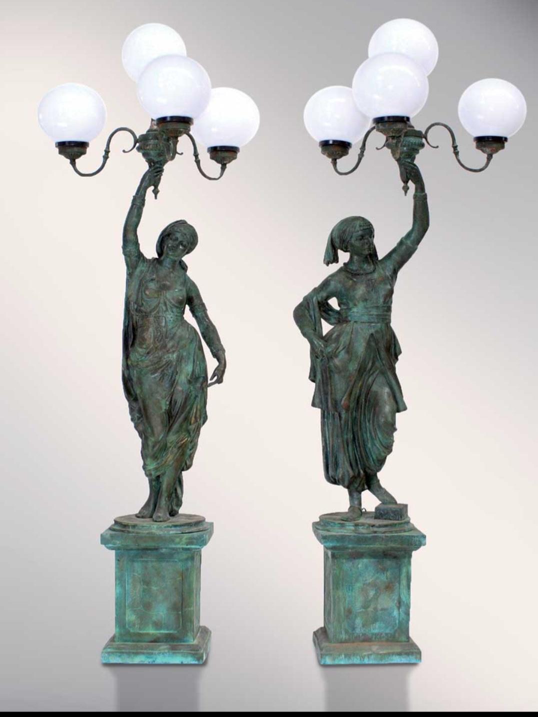 Imposing pair of monumental bronze figural torchères, crafted in Italy during the 20th century. Each sculpture depicts a full-length classical-style figure holding two ornate candelabra fitted with lights, combining decorative elegance with