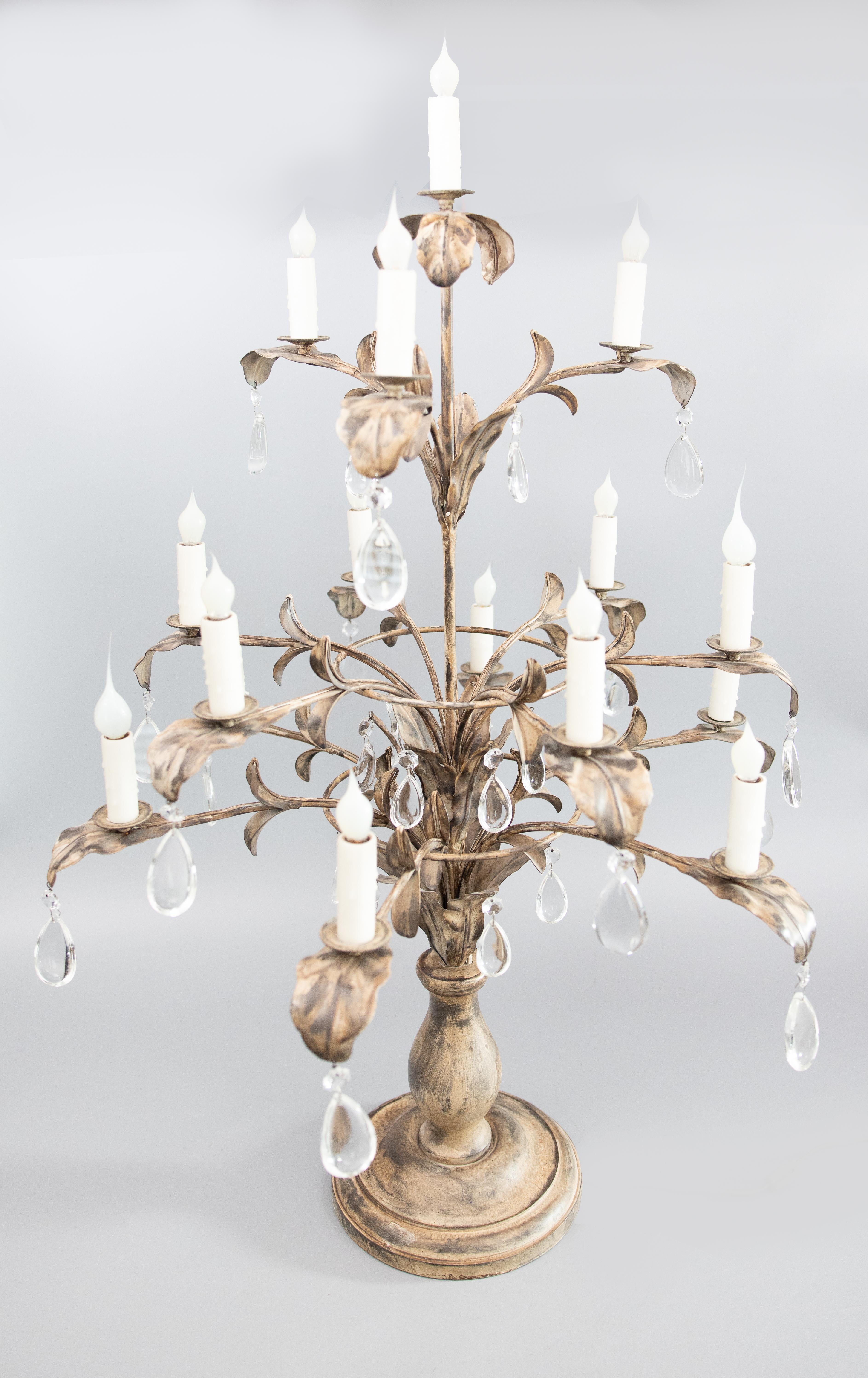 Pair of large, stately 16 light tole candelabras with turned wooden bases supporting metal foliate branches with crystal teardrop pendants, electrified. 

DIMENSIONS
29ʺW × 29ʺD × 43ʺH