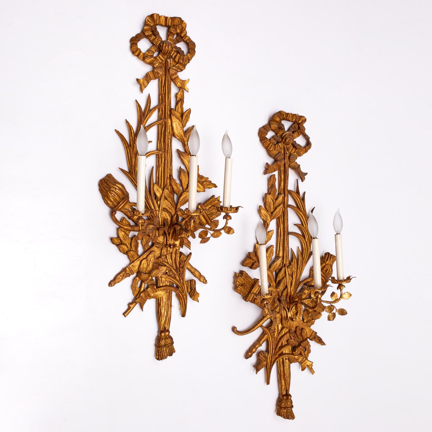 Pareja de monumentales apliques de madera tallada y dorada estilo Luis XVI, Siglo XX

Un llamativo par de apliques de pared franceses de gran tamaño estilo Luis XVI, ricamente tallados en madera dorada y tole dorado, cada uno con tres luces tipo
