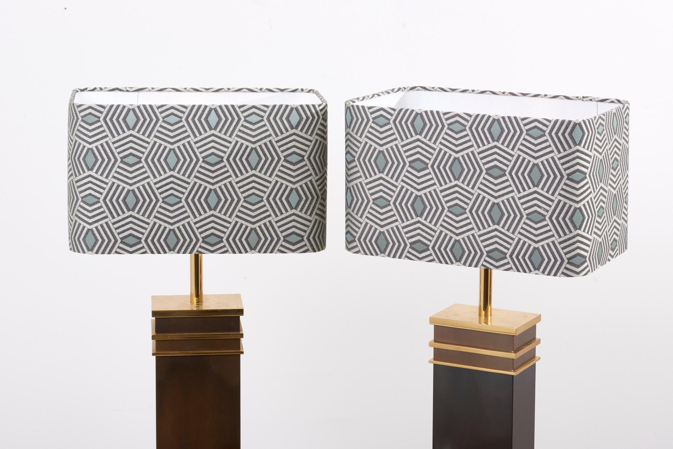 Set of two sculptural and extremely rare Mid-Century Modern table lamps in heavy, massive and partly patinated brass. Designed and manufactured by Vereinigte Werkstätten in Germany - 1960s. Including new custom made lamp shades with a graphic