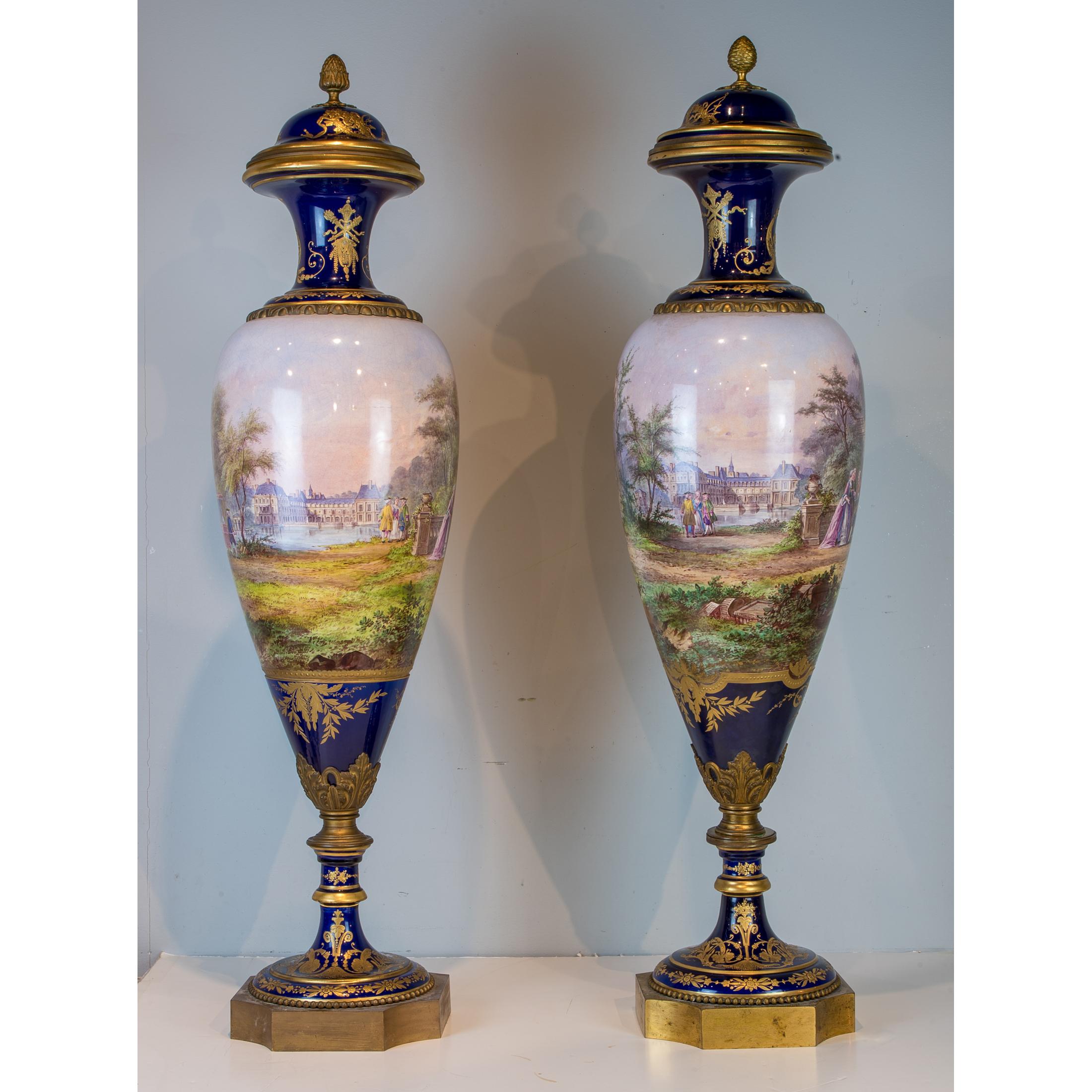 A Stunning monumental pair of Cobalt blue ground painted Sèvres porcelain vase and cover signed ‘H. Deprez.’

The paintings on the bodies of the vases are identical continuous paintings, depicting royal court members enjoying the lush grounds