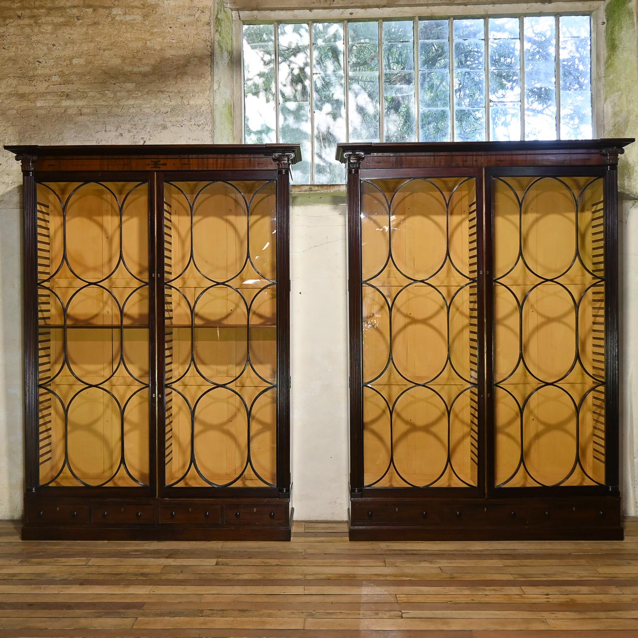 An extraordinary near pair of oversized Regency astral glazed library bookcases c.1810. 
Demonstrating a remarkable pair of full-length oval astragal glazed doors to each - with carved reeded detailing. The interior features a warm cadmium yellow