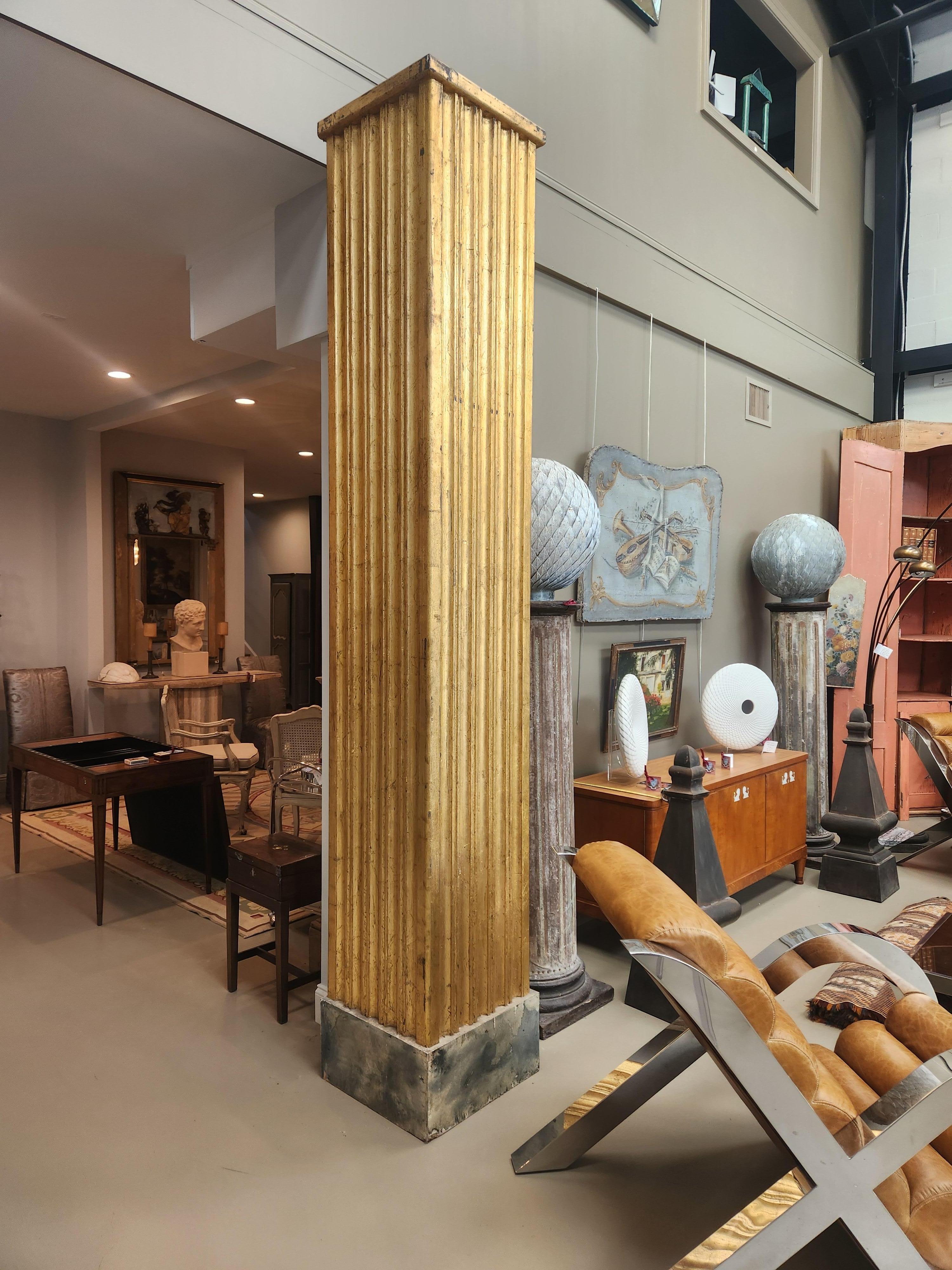An impressive pair of monumental giltwood columns, each featuring deep fluted detailing and a beautifully aged gold-leaf finish. Standing at a striking height (almost 10 feet tall) these columns command attention while remaining elegant and refined.