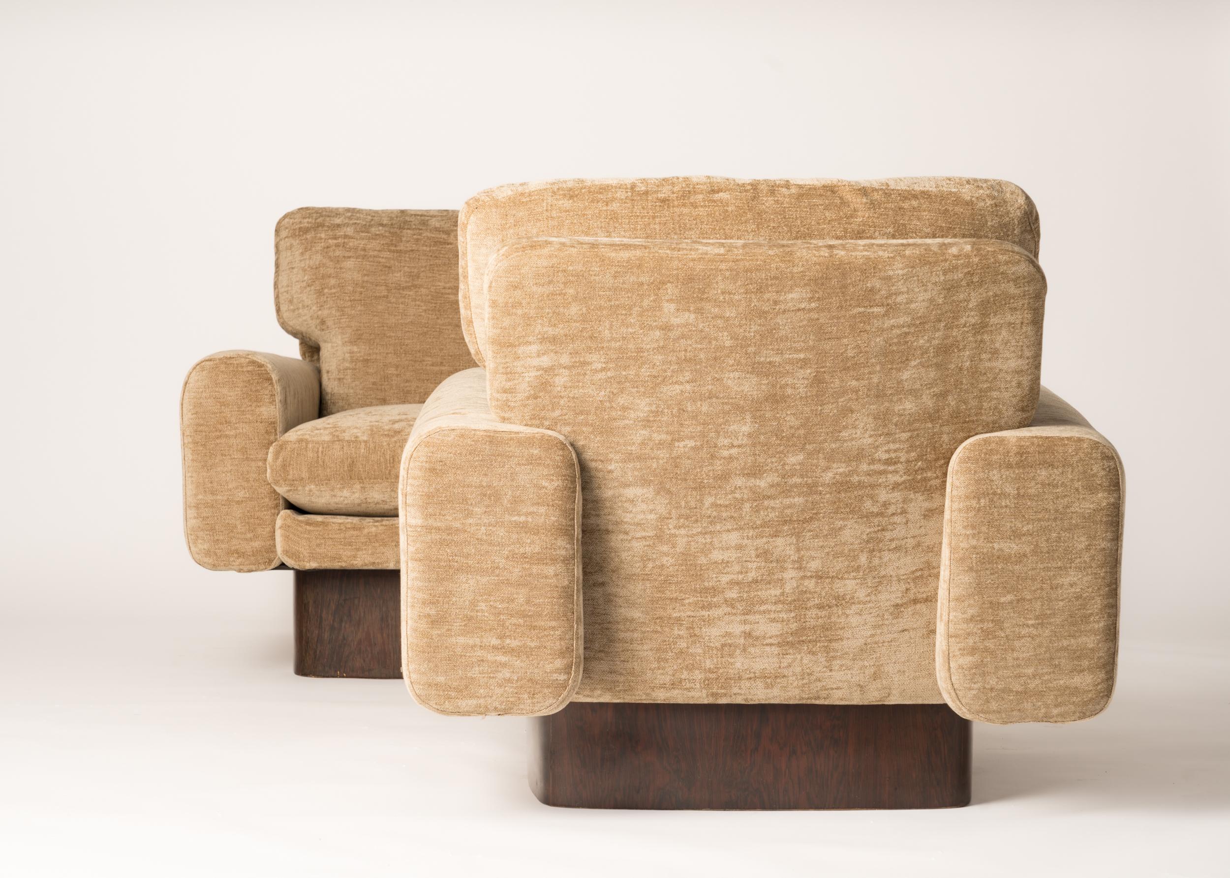 Pair of sculptural 1970's Italian armchairs made of two singular barrel shaped armrests and fluffy down filled cushions freshly re-upholstered with a luxurious silk blend golden brown velvet. The seats rest over circular walnut veneer wood