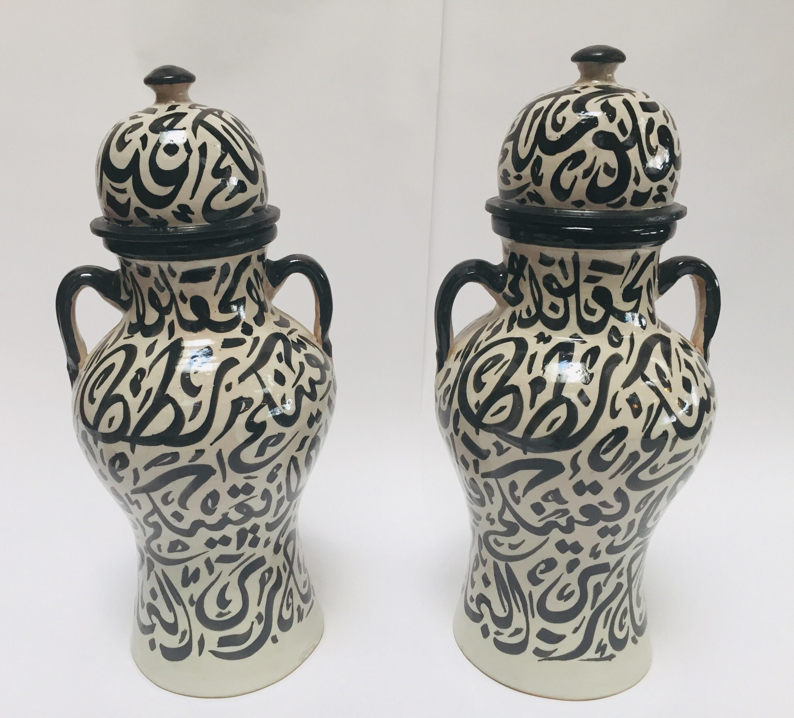 Pair of Moroccan glazed vintage ceramic decorative jars from Fez.
Moorish style ceramics vases handcrafted and hand painted in Fez with Arabic calligraphy writing design in black on ivory background.
This kind of Art Writing looks calligraphic is