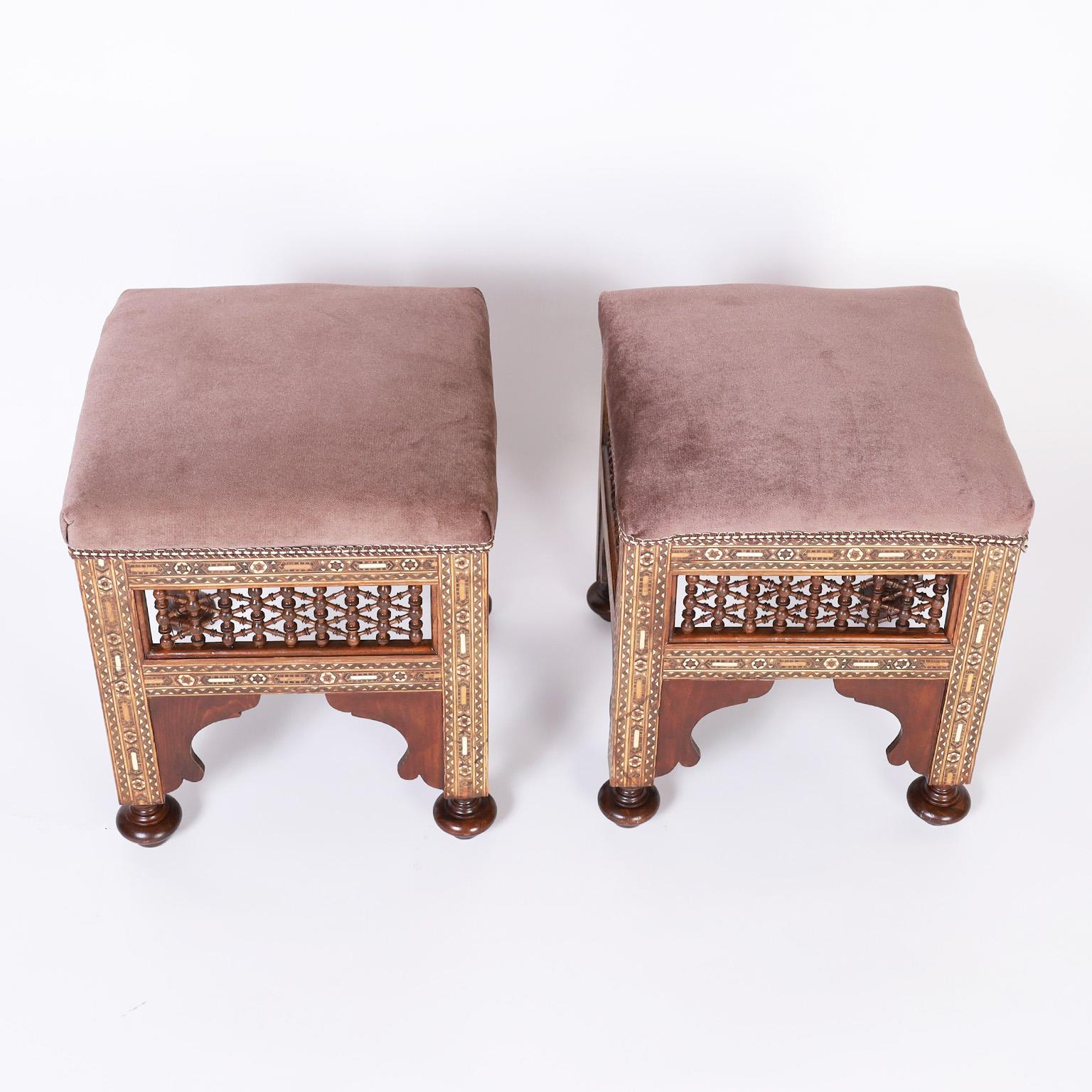 Pair of exotic near Eastern benches or stools with upholstered cushions over bases crafted in walnut featuring stick and ball panels, geometric inlays of bone, satinwood, and mahogany and moorish arches on turned feet.