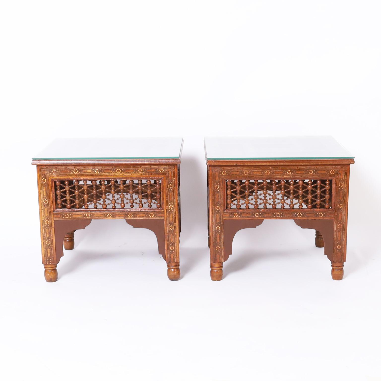 Intriguing pair of antique Moroccan stands with or without glass tops crafted in walnut featuring geometric inlays of bone, ebony, and kingwood, stick and ball panels, moorish arches, and turned feet.