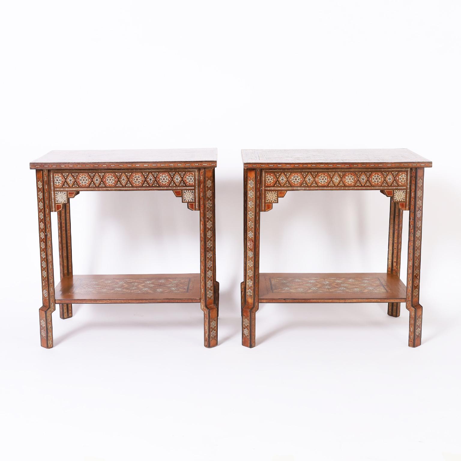 Standout pair of antique near eastern stands crafted in walnut and ambitiously inlaid with geometric micro mosaic marquetry consisting of bone, mother of pearl, ebony and mahogany on both tiers, legs and dog leg feet.