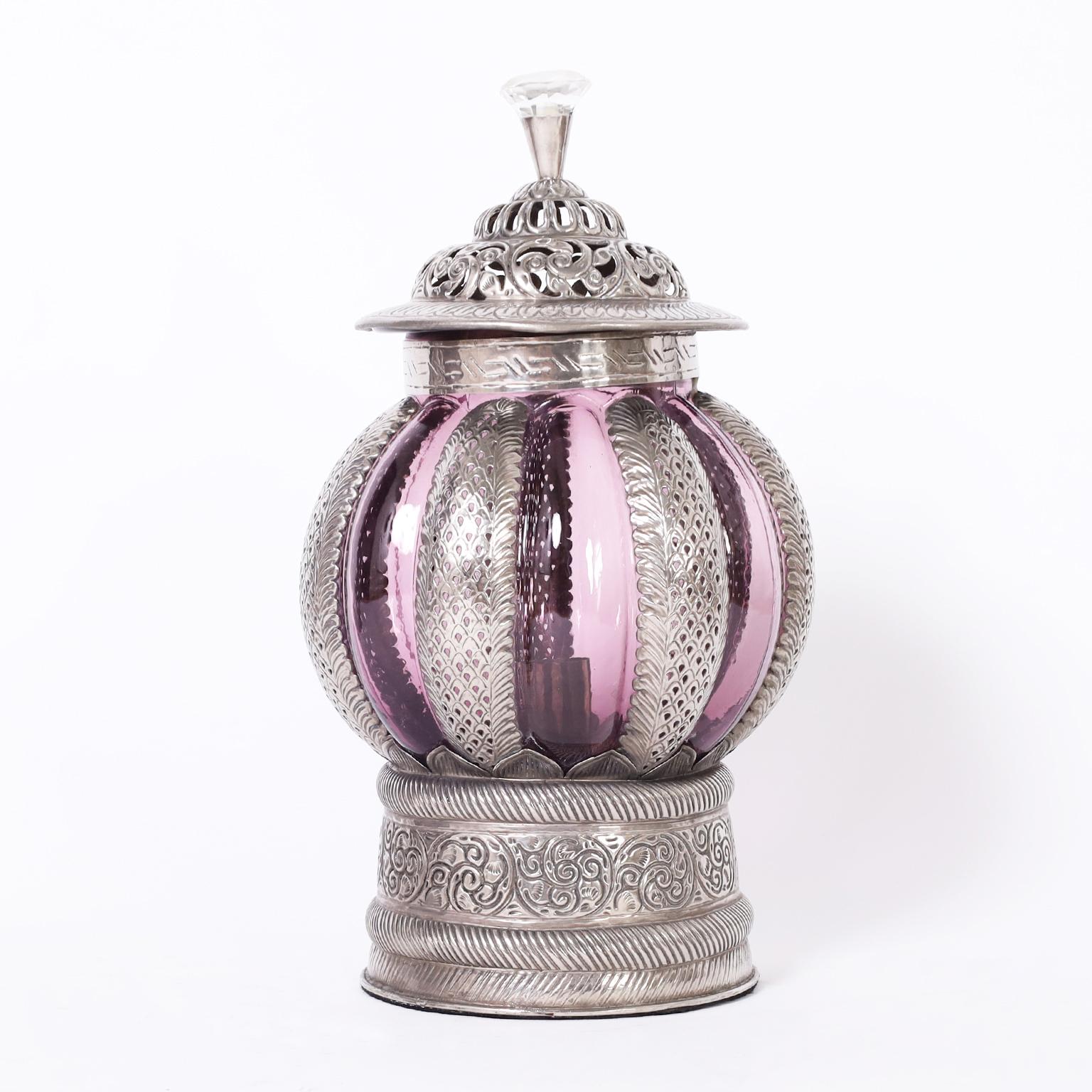 Intriguing pair of vintage Moroccan lanterns crafted in hand hammered metal work with floral designs and featuring cut glass handles and alluring hand blown amethyst glass shades.