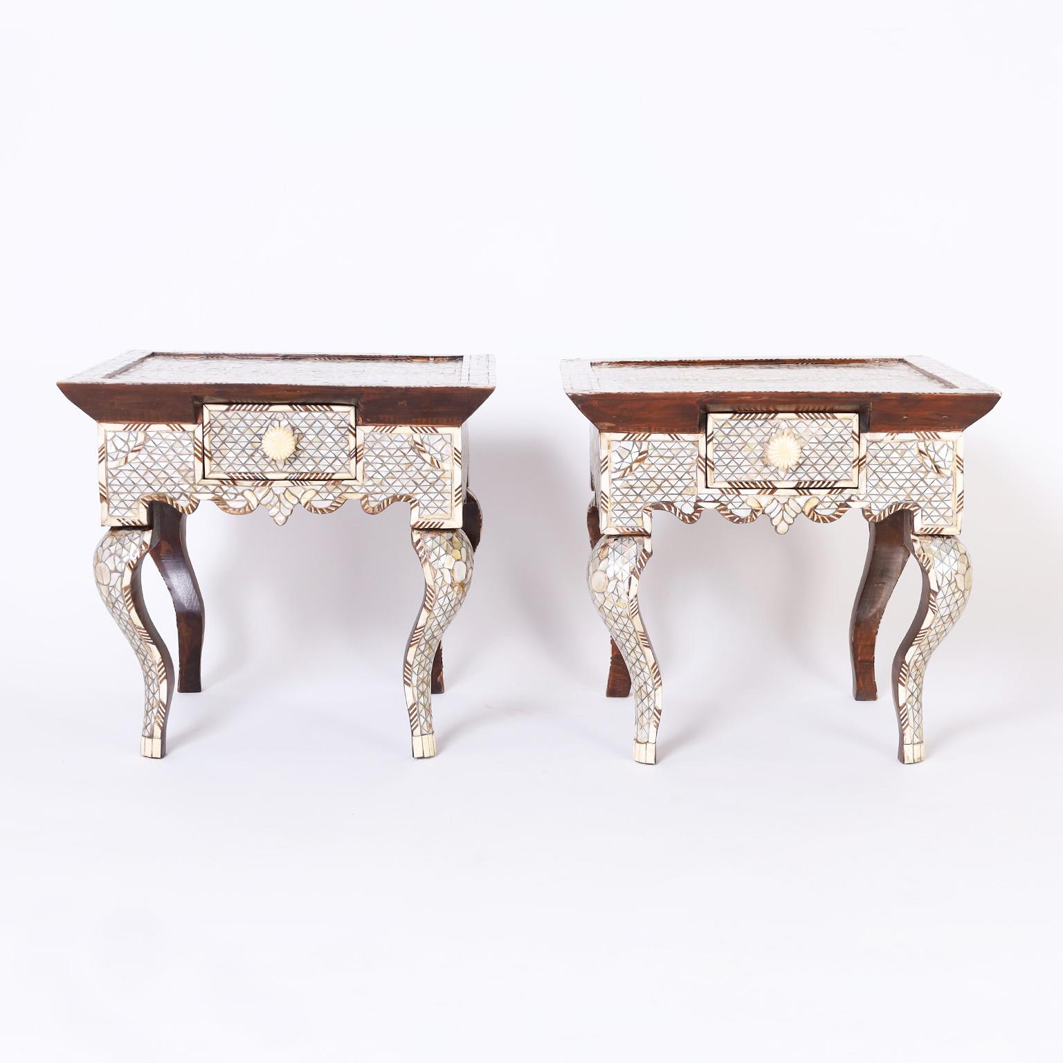 Pair of near eastern stands crafted in indigenous hardwoods in a dramatic form, featuring mosaics all around with mother of pearl, bone and walnut, one drawer with a carved bone pull, scalloped skirts, and cabriole legs.