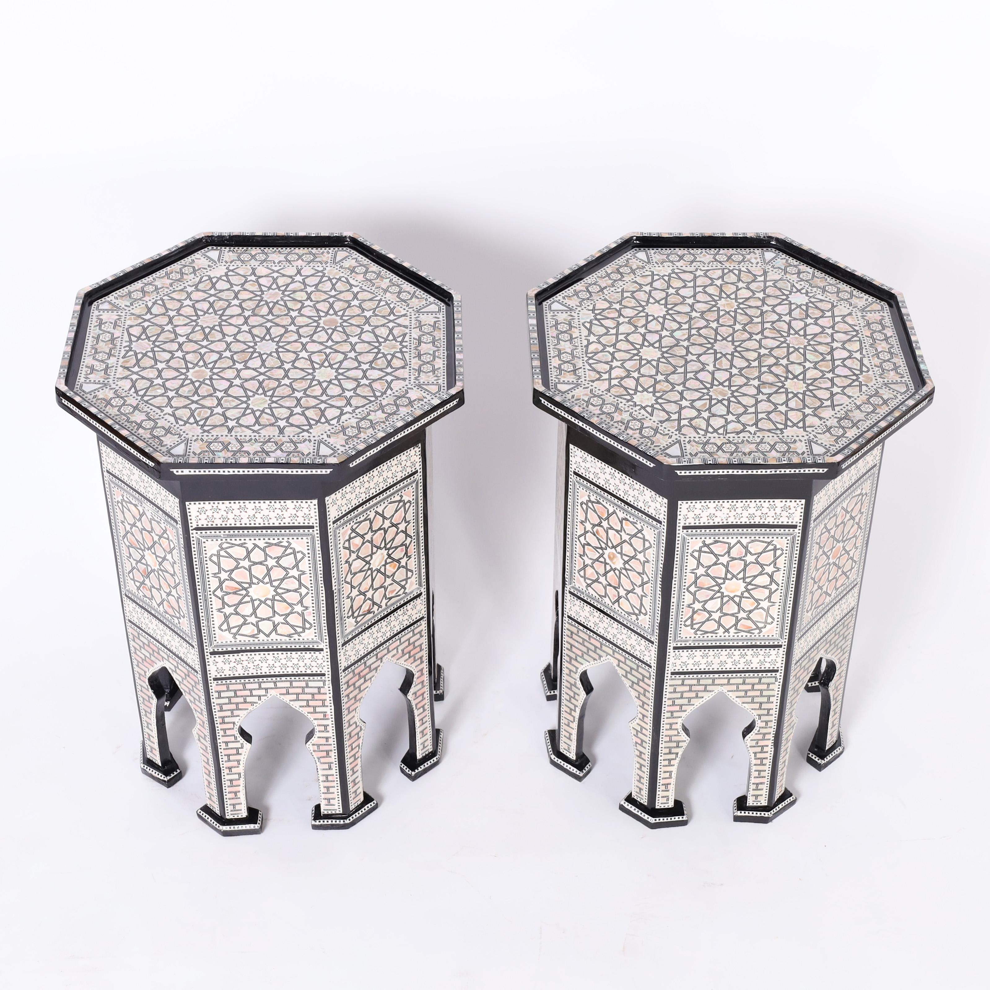 Standout pair of vintage Moroccan stands elaborately decorated in mother of pearl, ebony, and bone marquetry, having classic moorish octagon forms with architecturally interesting arched legs and featuring secret compartments lined in red velvet. 
