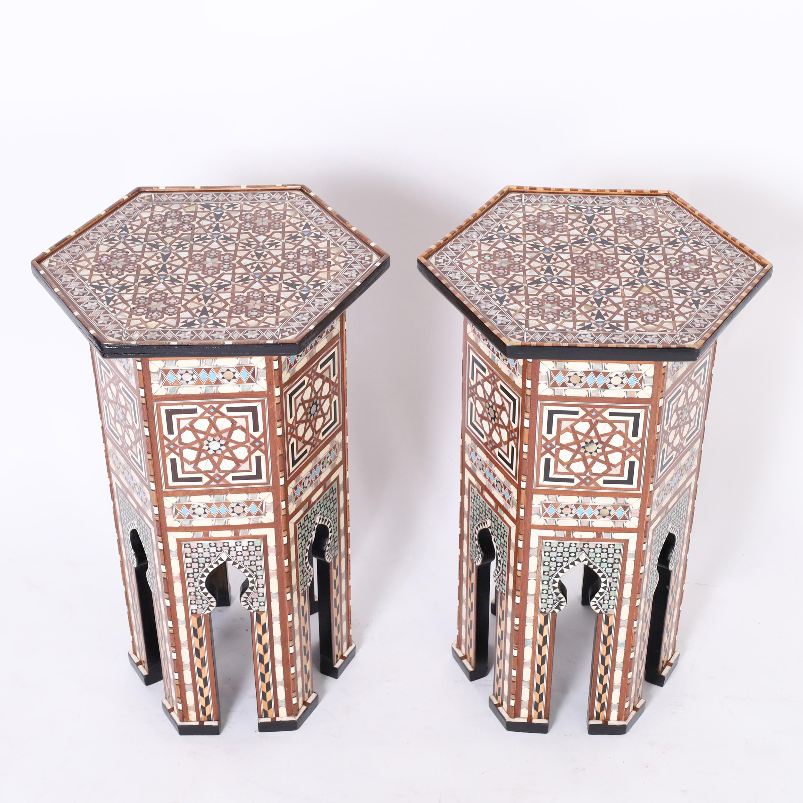 Standout pair of Moroccan stands or pedestals crafted in mahogany in a hexagon form with classic moorish arches and clad in elaborate inlaid marquetry of mother of pearl, ebony, bone, and blue painted bone in geometric designs. 
