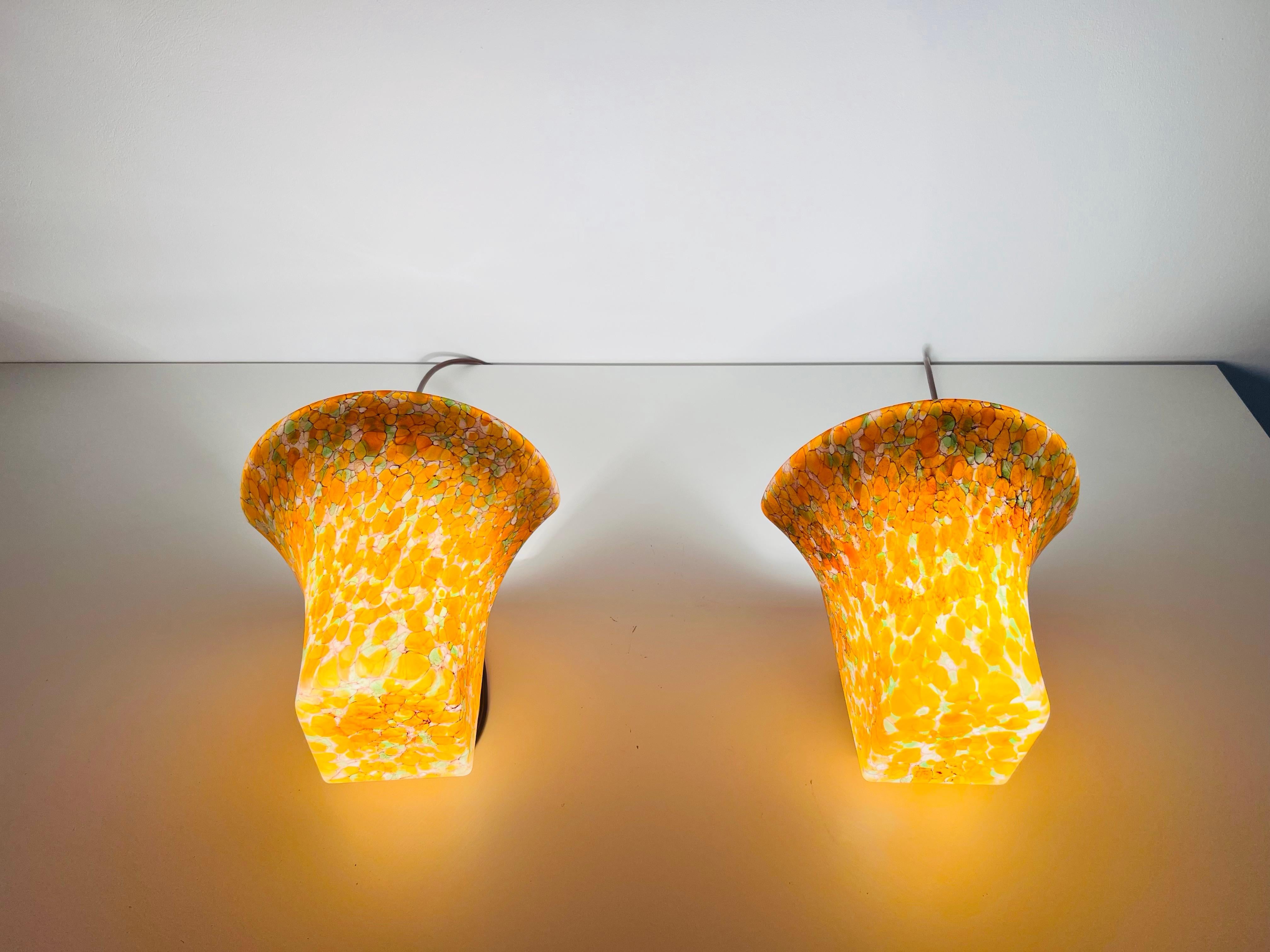This exceptional pair of mosaic glass wall lamps by Peill & Putzler, crafted in Germany in the 1960s, embodies the height of sophisticated mid-century design. Each lamp boasts a mosaic of rich orange and green glass tones, delicately set in an