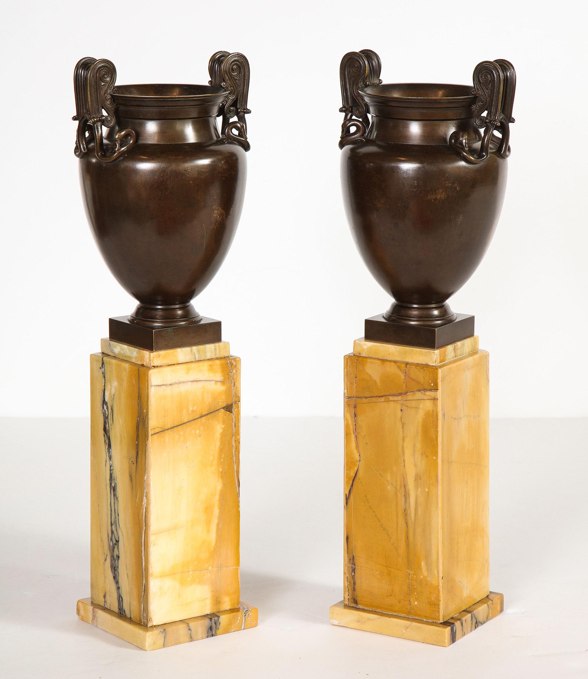 Pair of French Empire bronze urns on sienna marble stands

Each bronze urn with matching lid, flanked by scroll handles ending in a double swan head, all on a stepped sienna marble base.

 