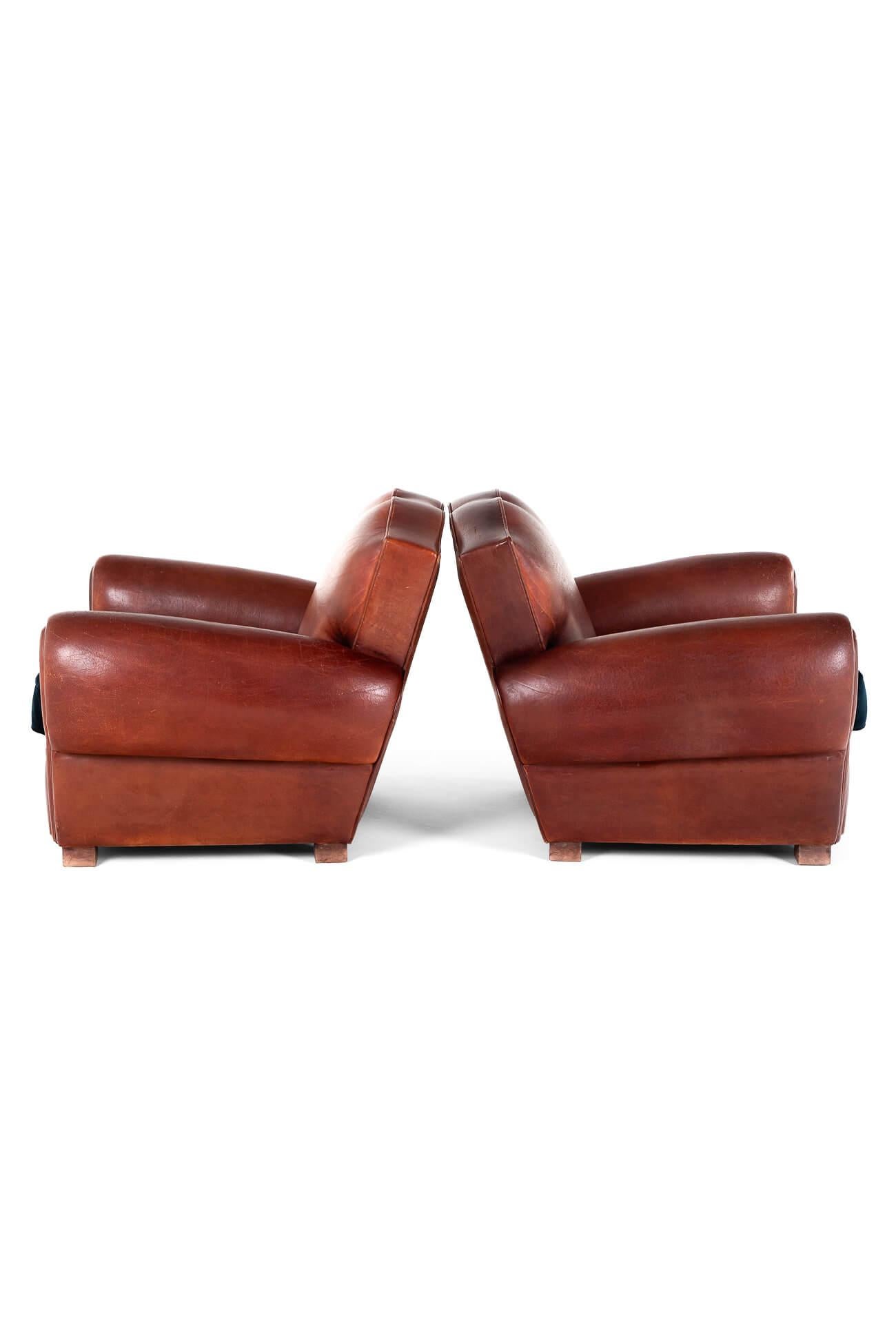 An exceptional pair of moustache back club chairs.

Generous cigar arms with deep seats over stuffed scroll backs.

Upholstered in a beautiful thick chestnut leather and raised on oak block feet.

Fully restored with new webbing and springs replaced