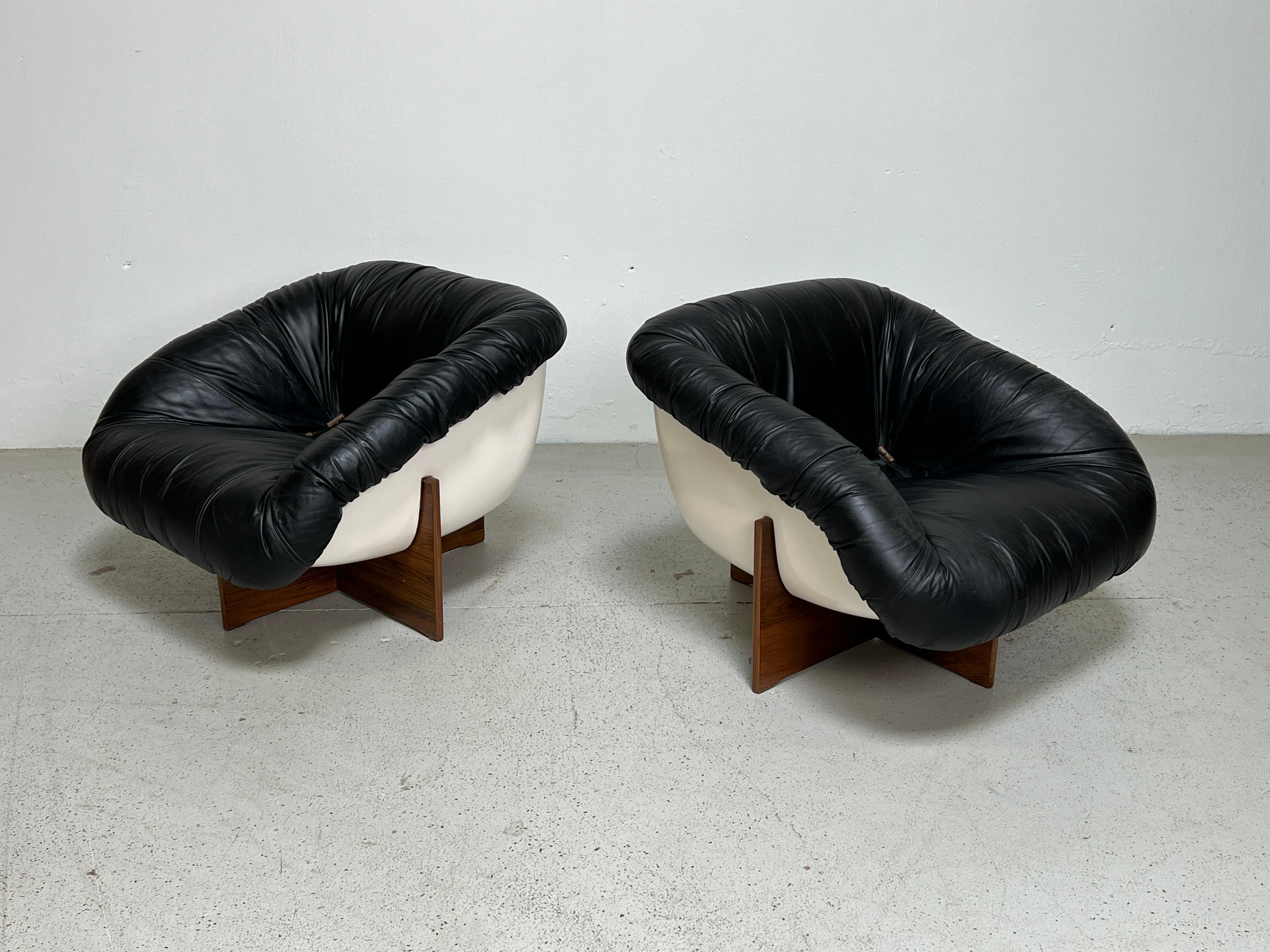 A rare pair of MP-61 lounge chairs with fiberglass frames, patinated leather and rosewood bases designed by Percival Lafer. The black leather has a beautiful warm patina and is incredibly comfortable. 