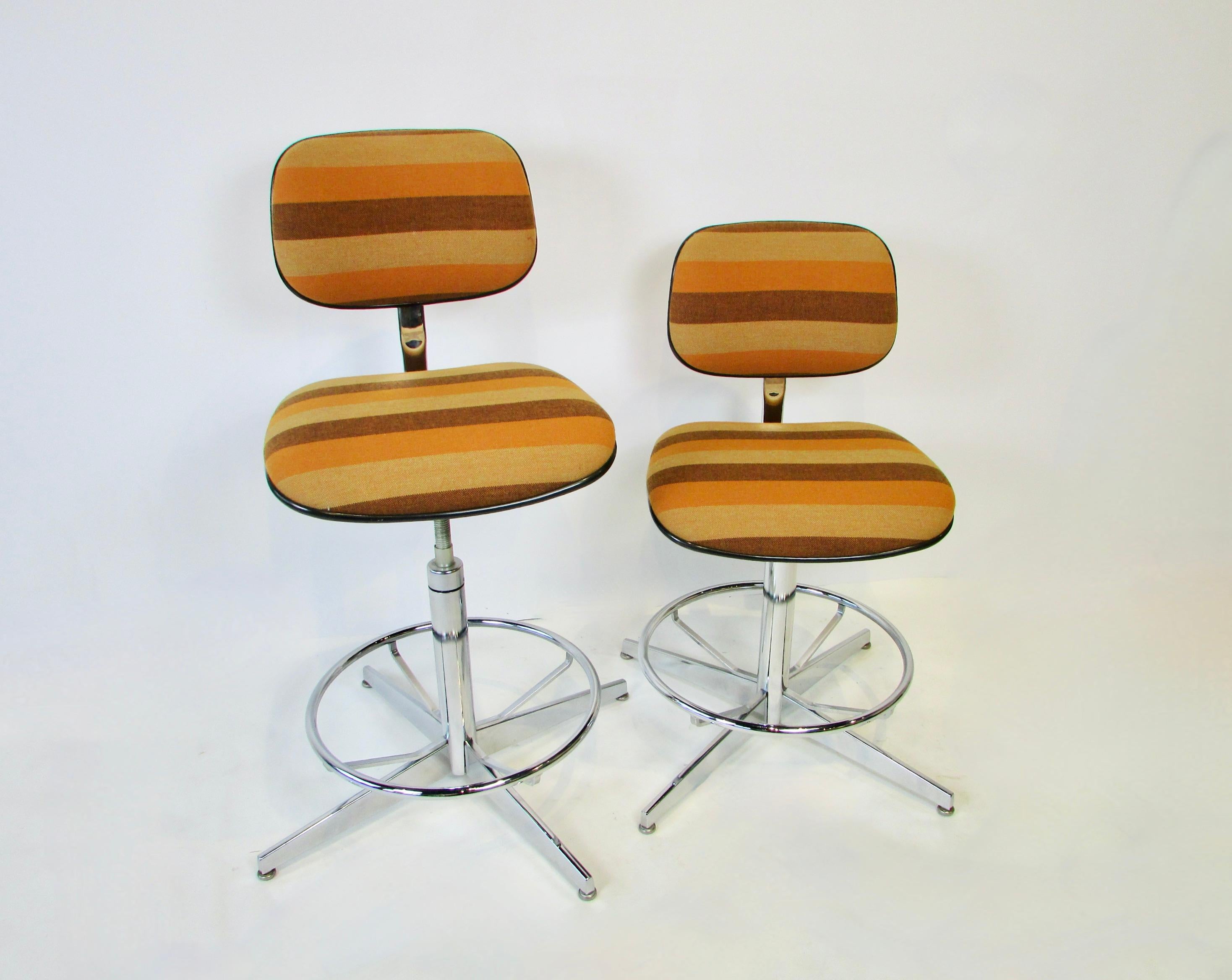 Pair of Steelcase co. adjustable operator bar counter stools. Upholstered in Alexander Girard attributed brown and gold striped textile. Excellent condition through out chrome and upholstery. Stools are multi adjustable. Seat height is listed at 35