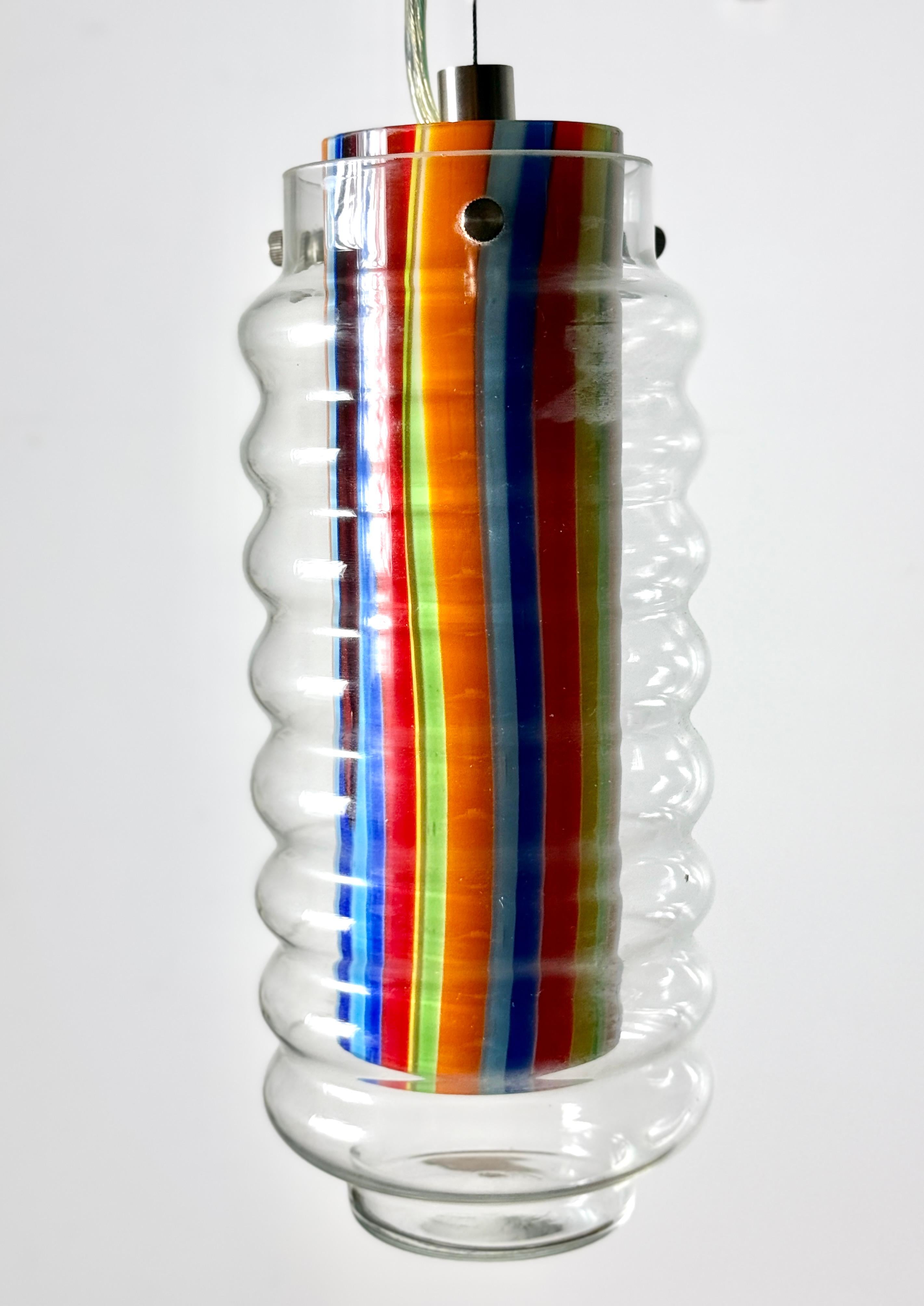 Paire de suspensions en verre d'art coloré
Vendu par Kovacs lighting vers les années 1990

Extérieur en verre clair ondulé avec un abat-jour cylindrique intérieur composé de bandes verticales colorées dans des couleurs vives et modernes.

Jamais