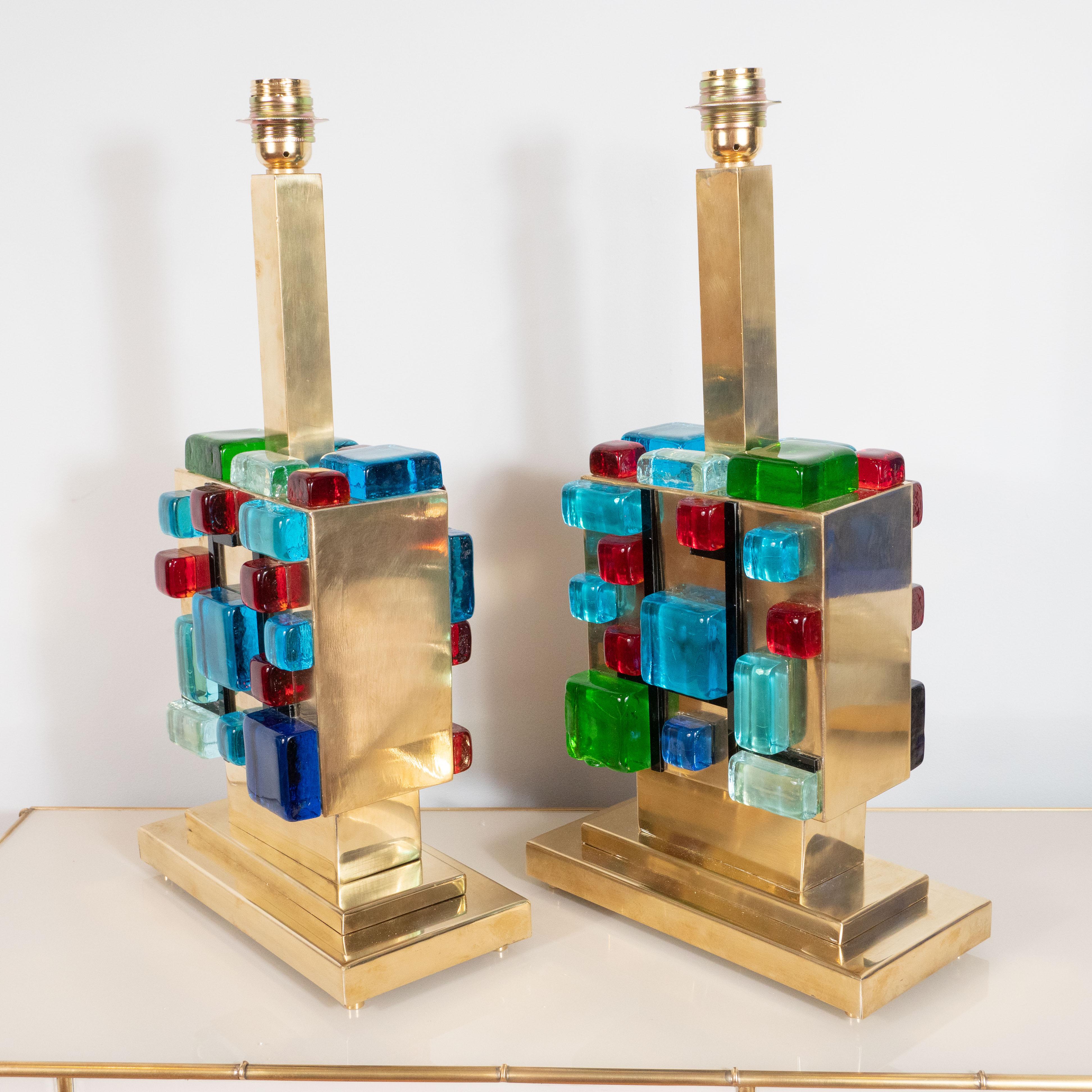 These rare and vibrant pair of lamps consist of multi-colored (red, blue, turquoise, green and clear) Murano glass square blocks arranged in a geometric shape on top of a square polished brass base, allowing the brass to show through. A unique and