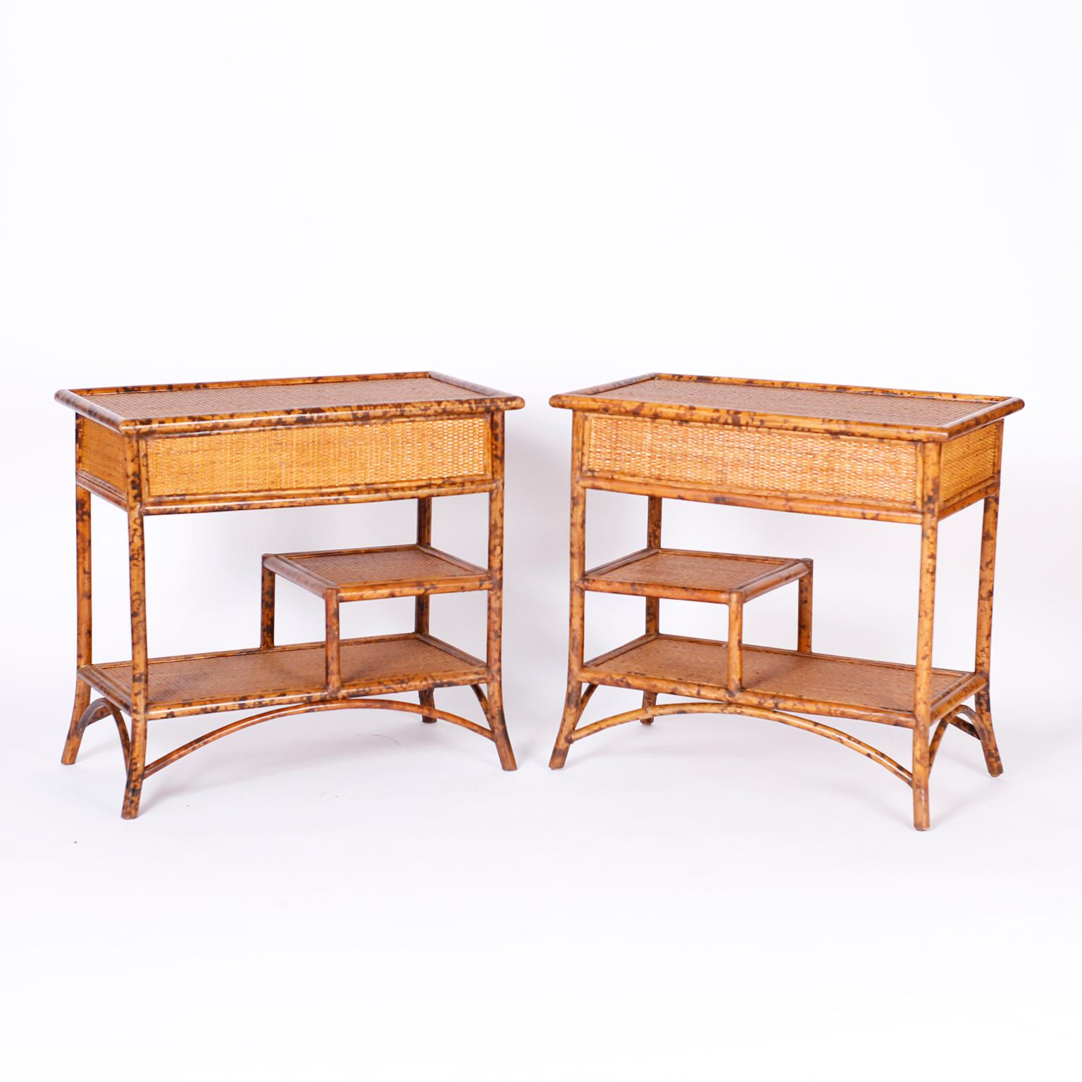 Pair of mid century British colonial stands with faux burnt bamboo frames, grasscloth panels on the tops, sides and shelves, all over splayed legs.