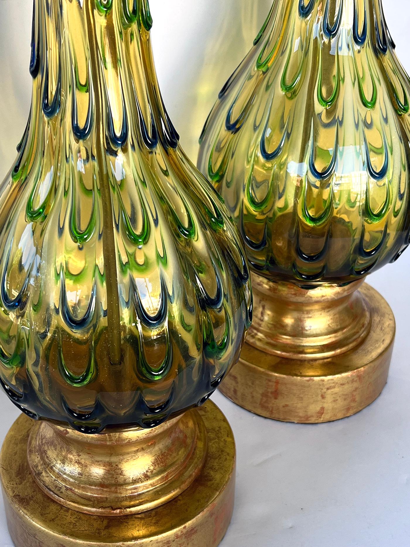 each bottle-form lamp of gold glass decorated overall with a watery blue and green thumb-print drip pattern; resting on a gilt-metal base