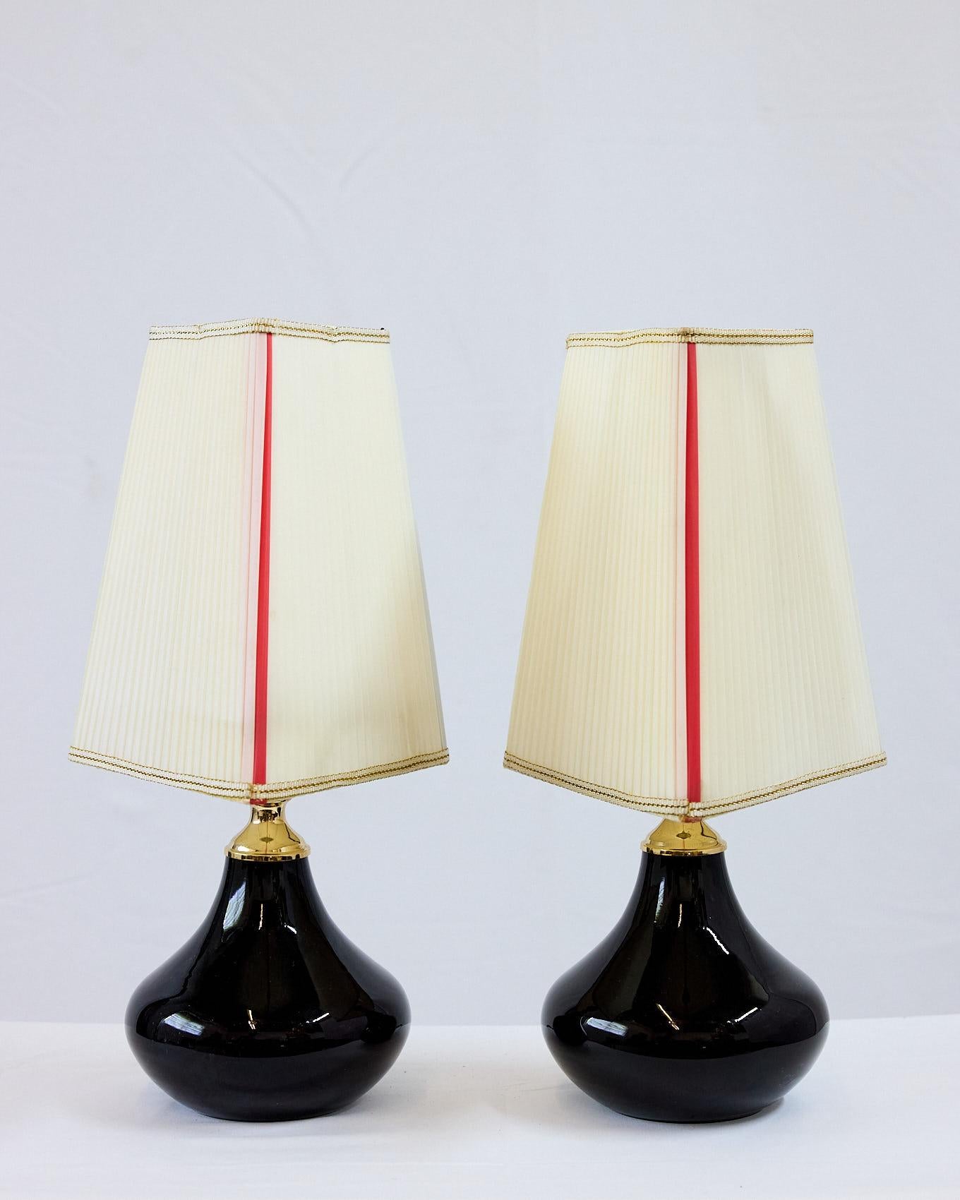 Paire de petites lampes uniques du 20e siècle avec des bases en verre améthyste de Murano soufflé à la main et éclairé. Elles sont en laiton poli et sont dotées d'un abat-jour triangulaire plissé de couleur ivoire avec des accents d'angle en noir,