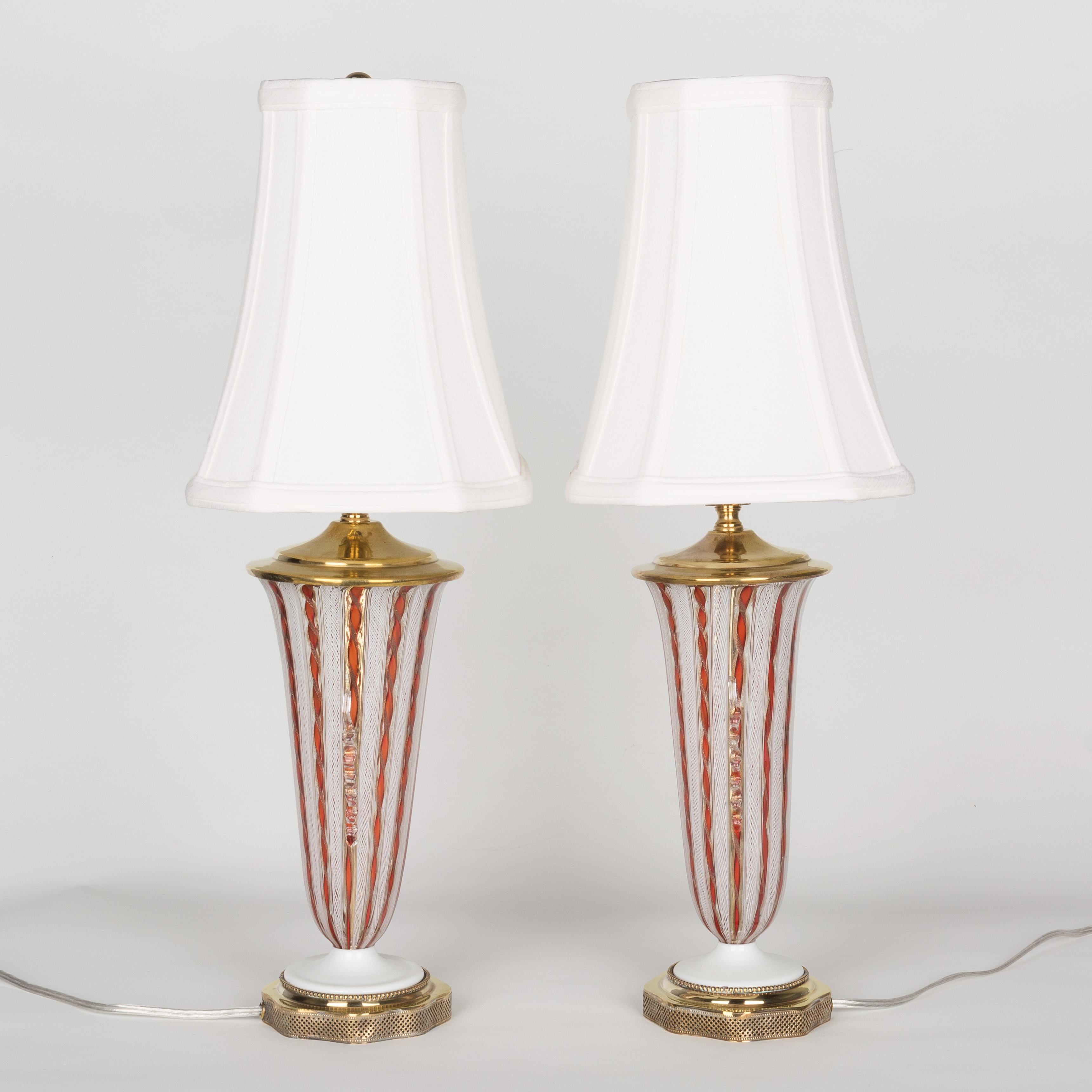 A pair of small Murano latticino glass lamps by A.Ve.M. (Arte Vetraria Muranese). Alternating stripes of Zanfirico white lattice and canes of deep orange red twisted with shimmering copper. Delicate gold infused clear glass ribbons adorn the sides.