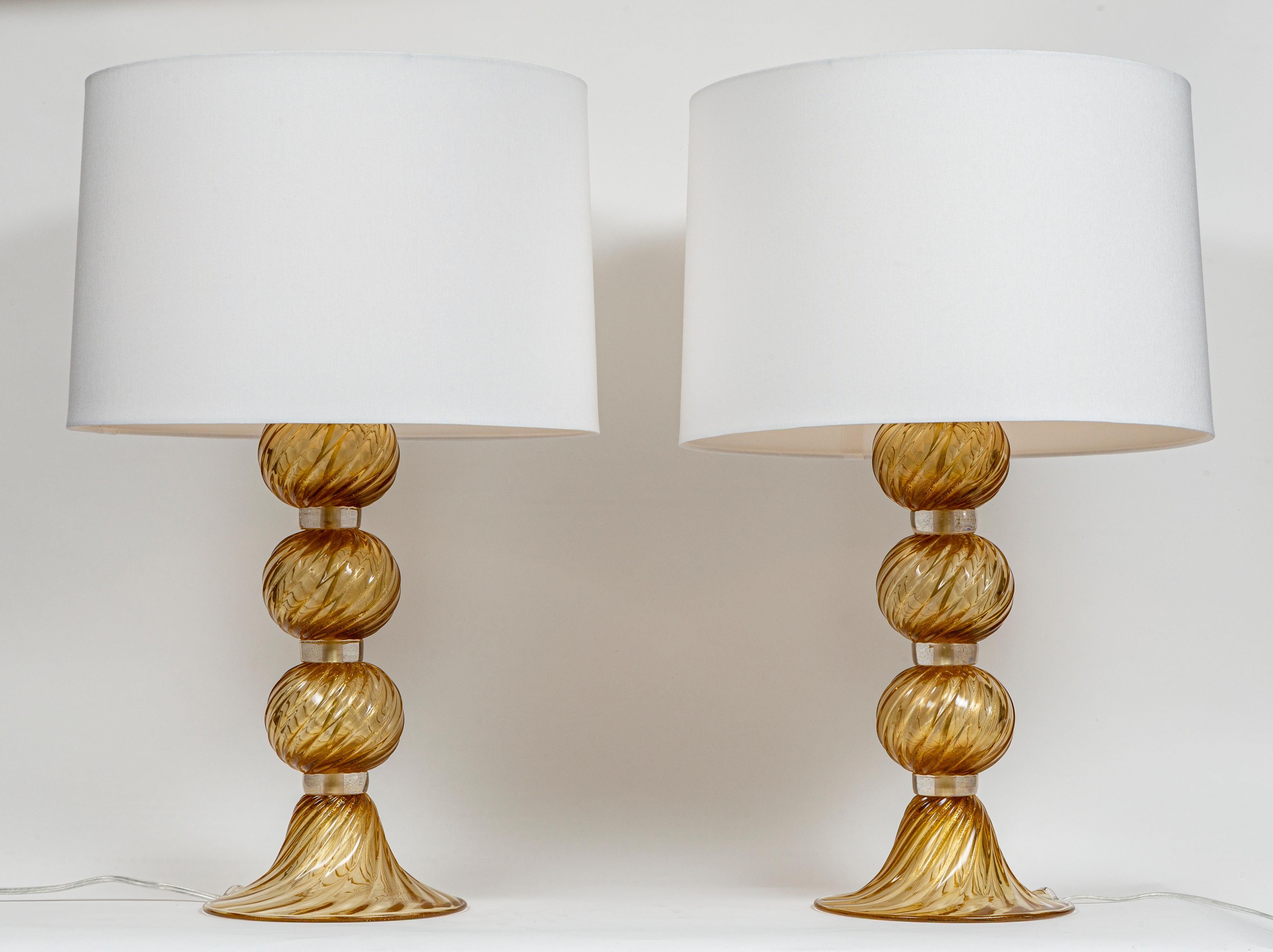 Beautiful pair of artisan blown amber and gold spiral sphered lamps joined by clear glass disks and finishing on a beautiful scalloped base.
Each electrified to US code for one E26 bulb. Shade shown included.
Dating: new, artisan work
Origin: