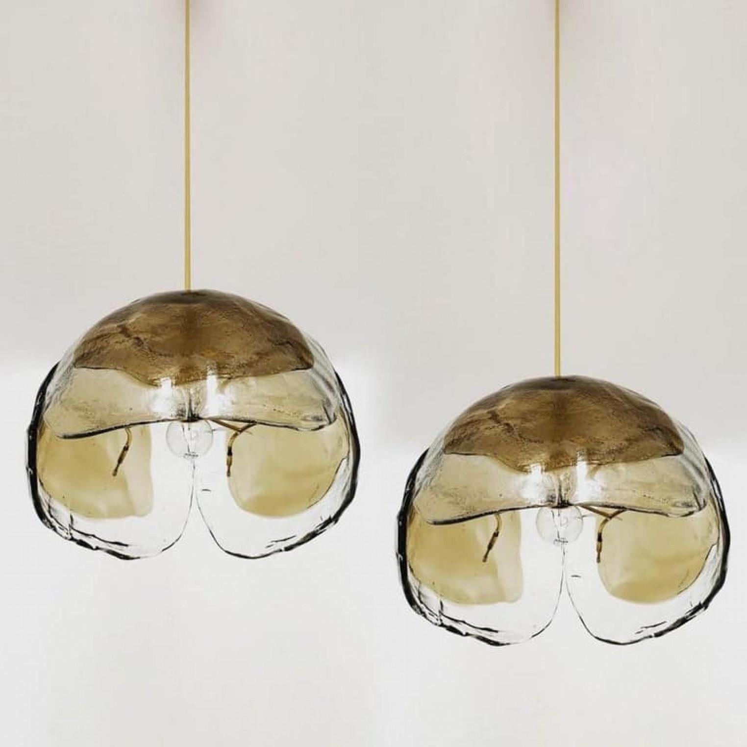 A pair of very nice pendant lights manufactured in mid century, circa 1970. Three smoke or amber tone Murano glasses are mounted on a brass fixture. Delivery with rod ore chain.

The crystal leaves are refracting the light in a beautiful way. It