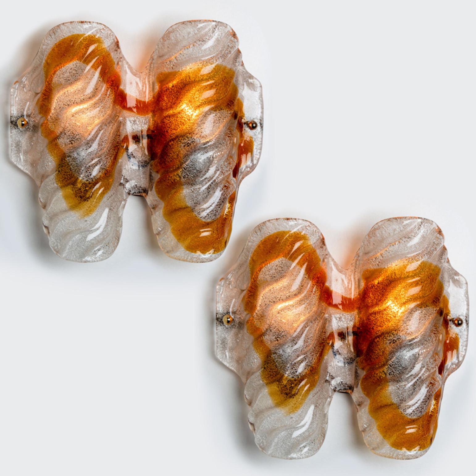 A pair of  beautiful wall lights, manufactured in the Mid Century, circa 1970 (end of 1960s and beginning of 1970s).

A brass frame and a bi-colored (clear and orange) hand blown Murano glass. Each piece of glass meticulously hand formed in clear