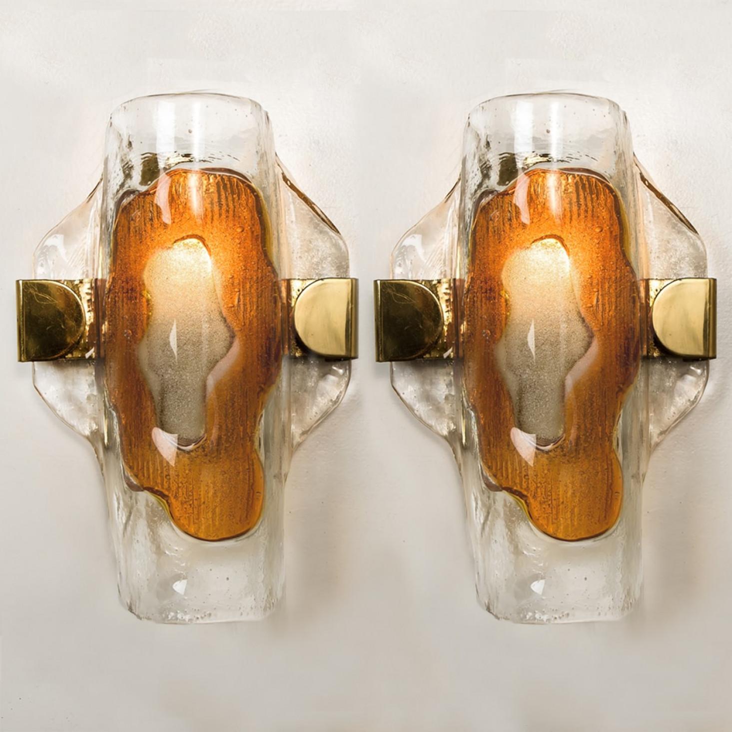 A pair of  beautiful wall lights, manufactured in the Mid Century, circa 1970 (end of 1960s and beginning of 1970s).

A brass frame and a bi-colored (clear and orange) hand blown Murano glass. Each piece of glass meticulously hand formed in clear