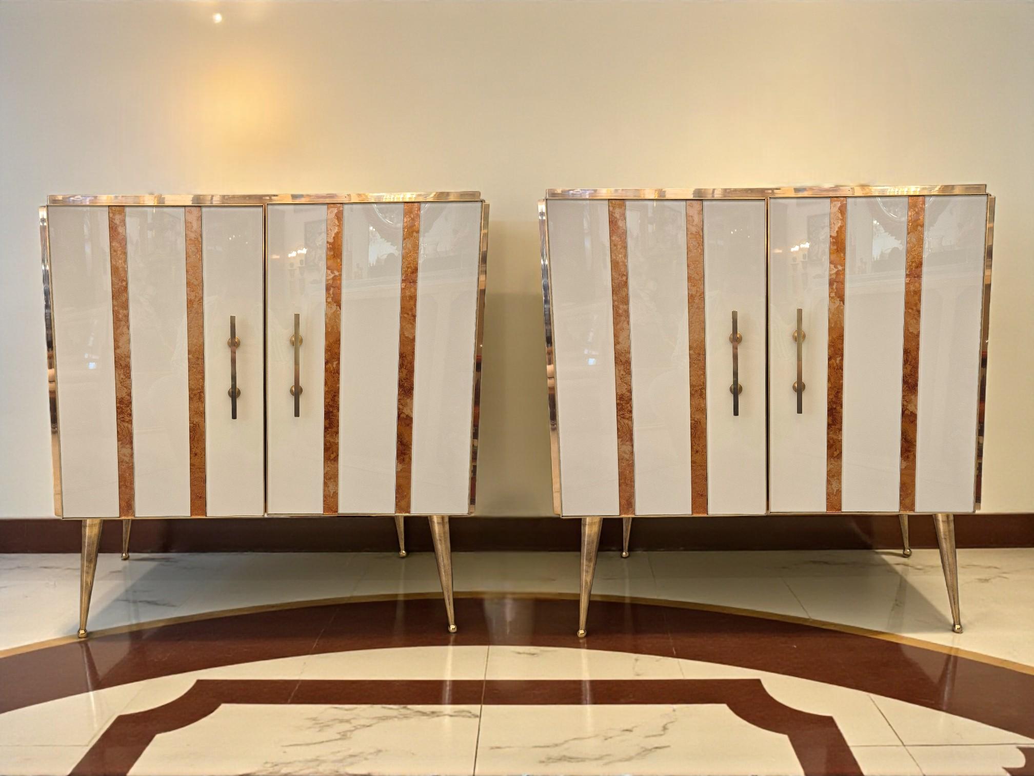 Bring a touch of timeless Italian sophistication into your interior with this exceptional pair of Murano glass and gilded brass cabinets, crafted in Italy circa 1960/1970.

Each piece is clad in alternating glossy cream and amber-toned Murano glass